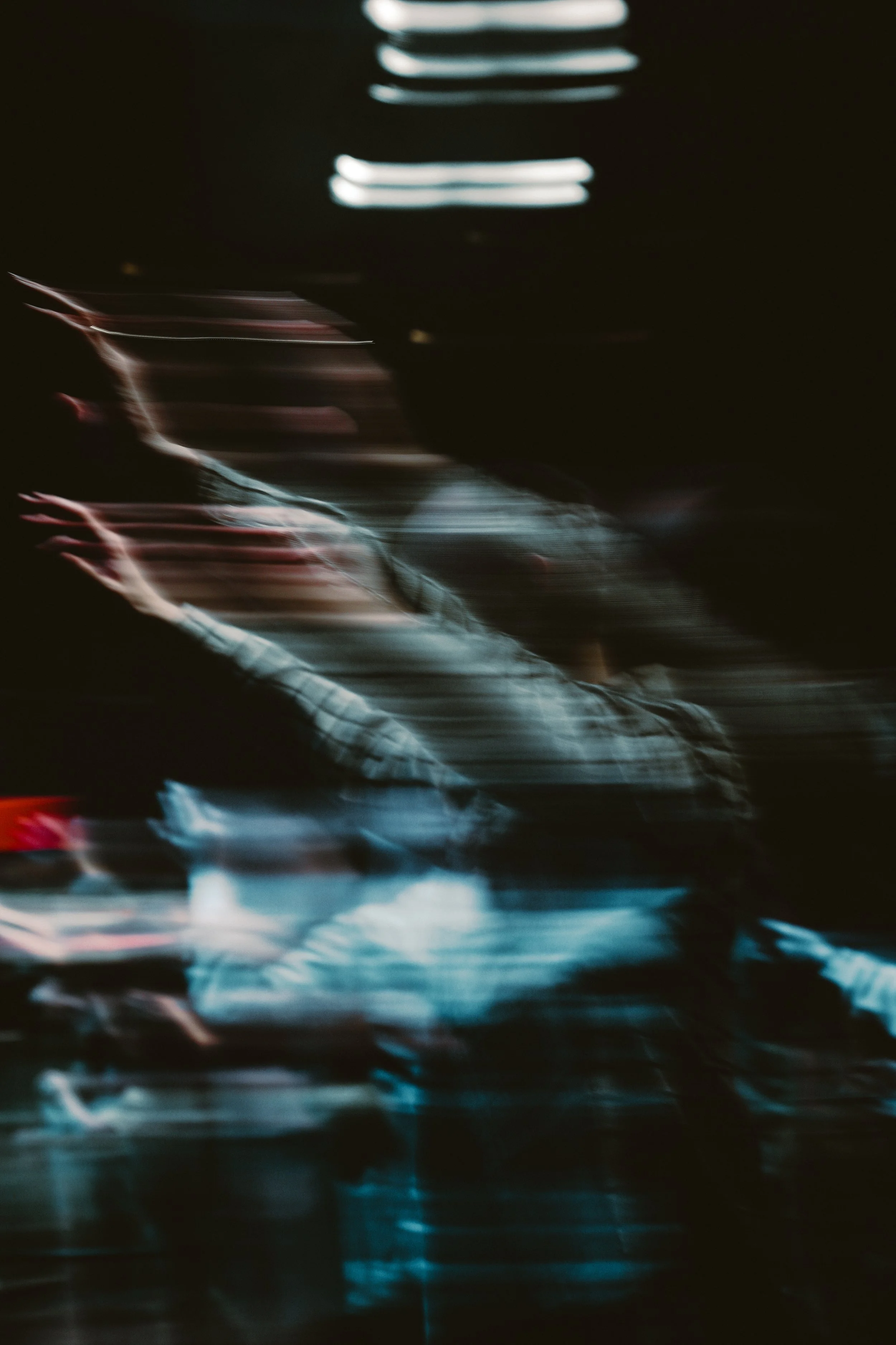 Blurred motion picture of a hand reaching out, with streaks of light and dark surrounding it, creating an abstract, dynamic scene.