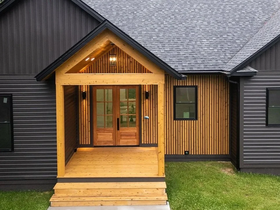 Covered front entry at 20 Merrifield Road featuring natural wood accents, double glass doors and contrasting dark siding.