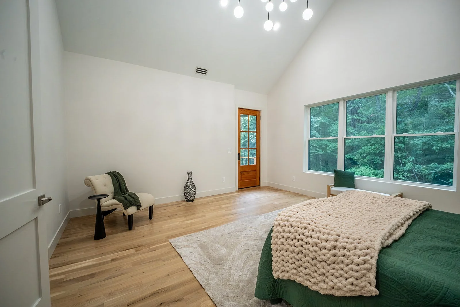 Primary suite at 20 Merrifield Road featuring cathedral ceilings, white oak flooring, large windows and views of the wooded setting.