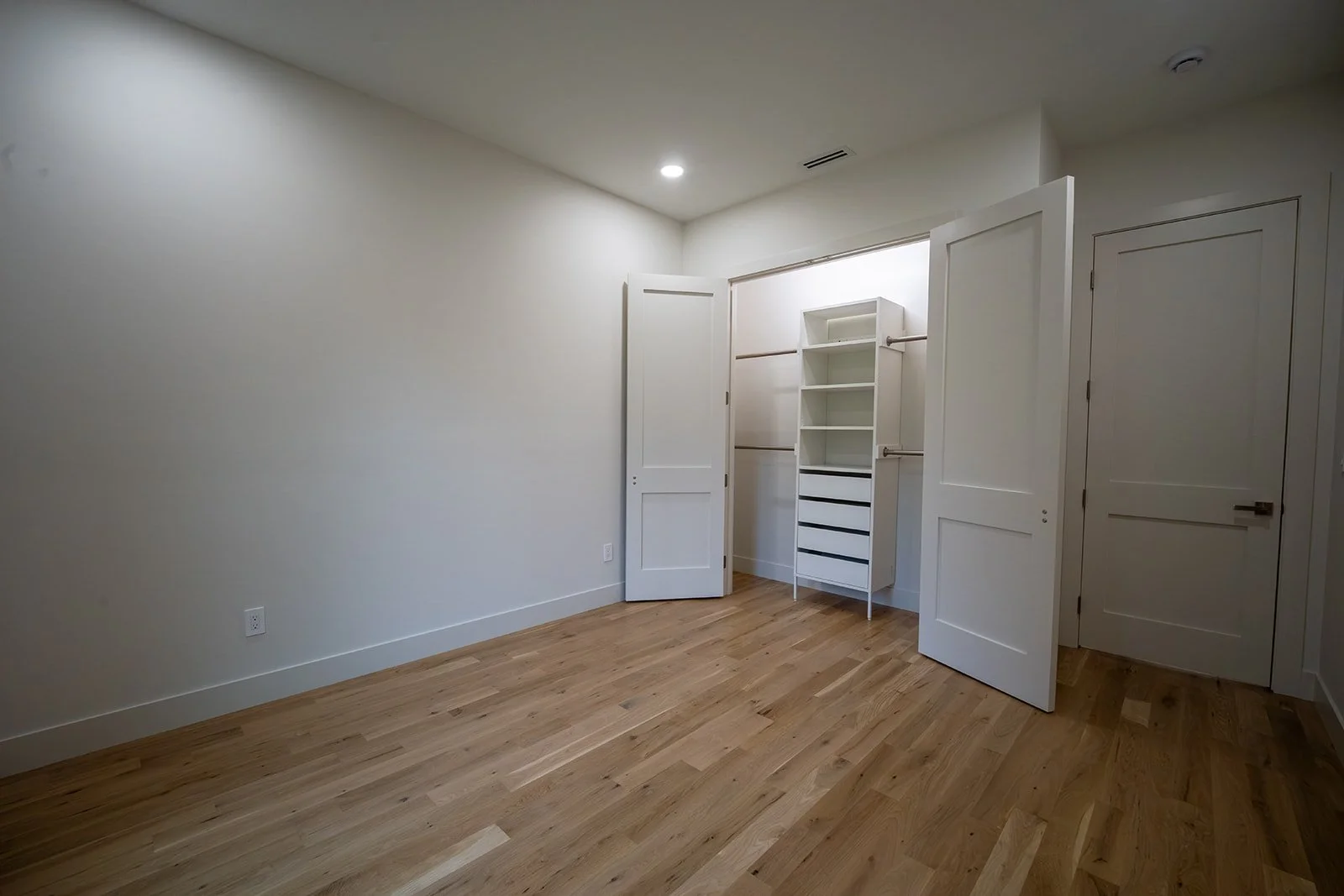 Third bedroom with white oak flooring and built-in closet storage system.