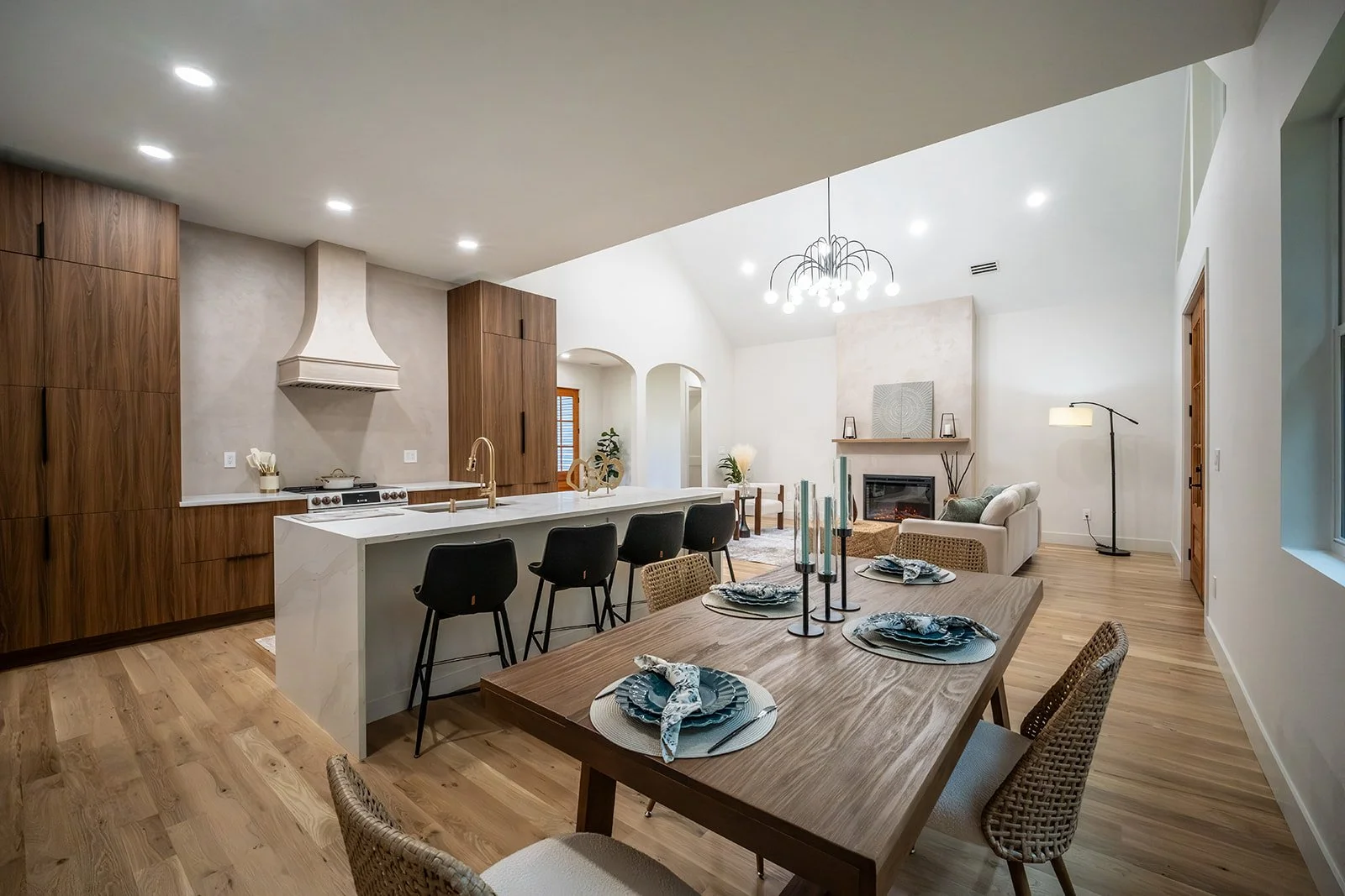 Open-concept kitchen and living area featuring white oak flooring, custom cabinetry, large center island and modern fireplace.
