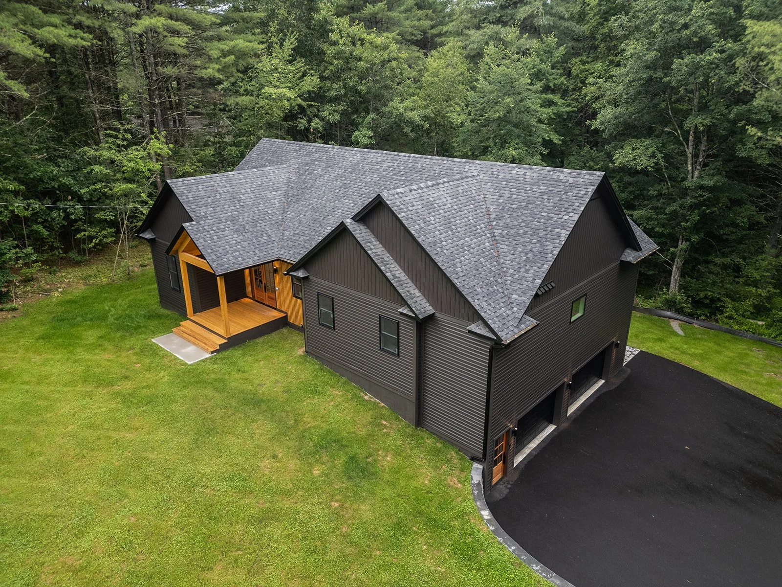 Aerial view of 20 Merrifield Road in Bernardston, MA, featuring the contemporary home, paved driveway and wooded 2.5-acre setting.
