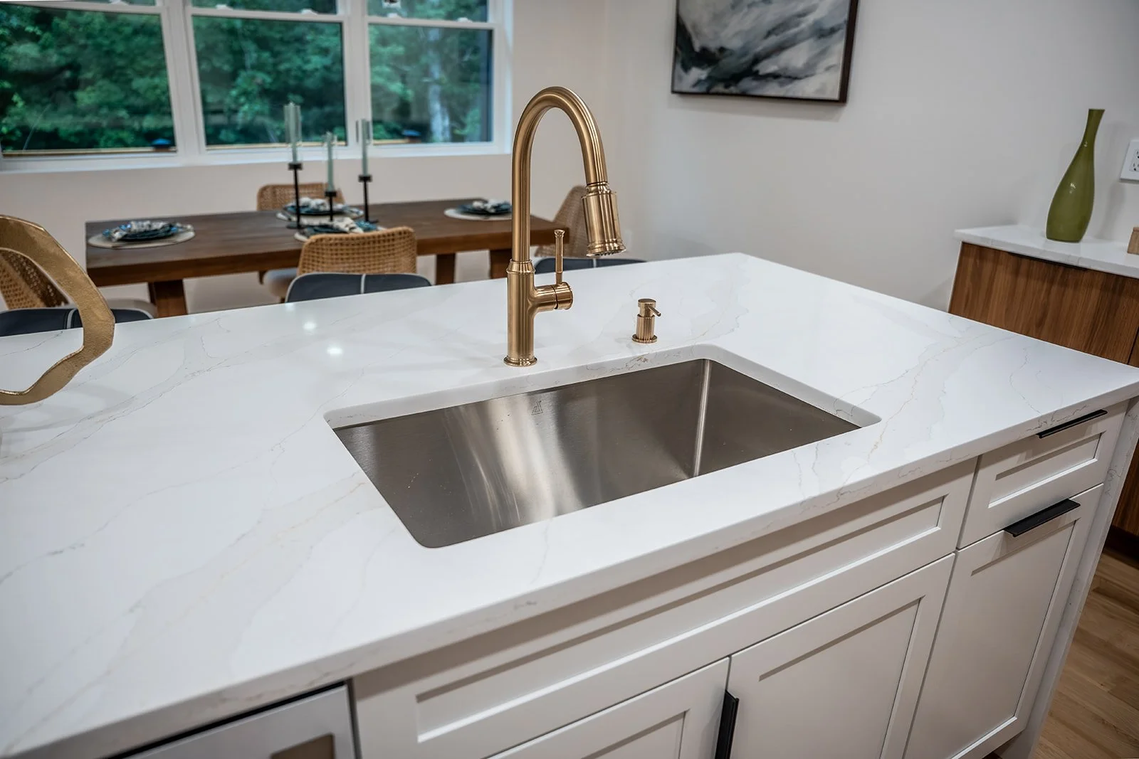 Oversized kitchen island with quartz countertops, undermount sink and brushed gold fixtures overlooking the open-concept living and dining space.