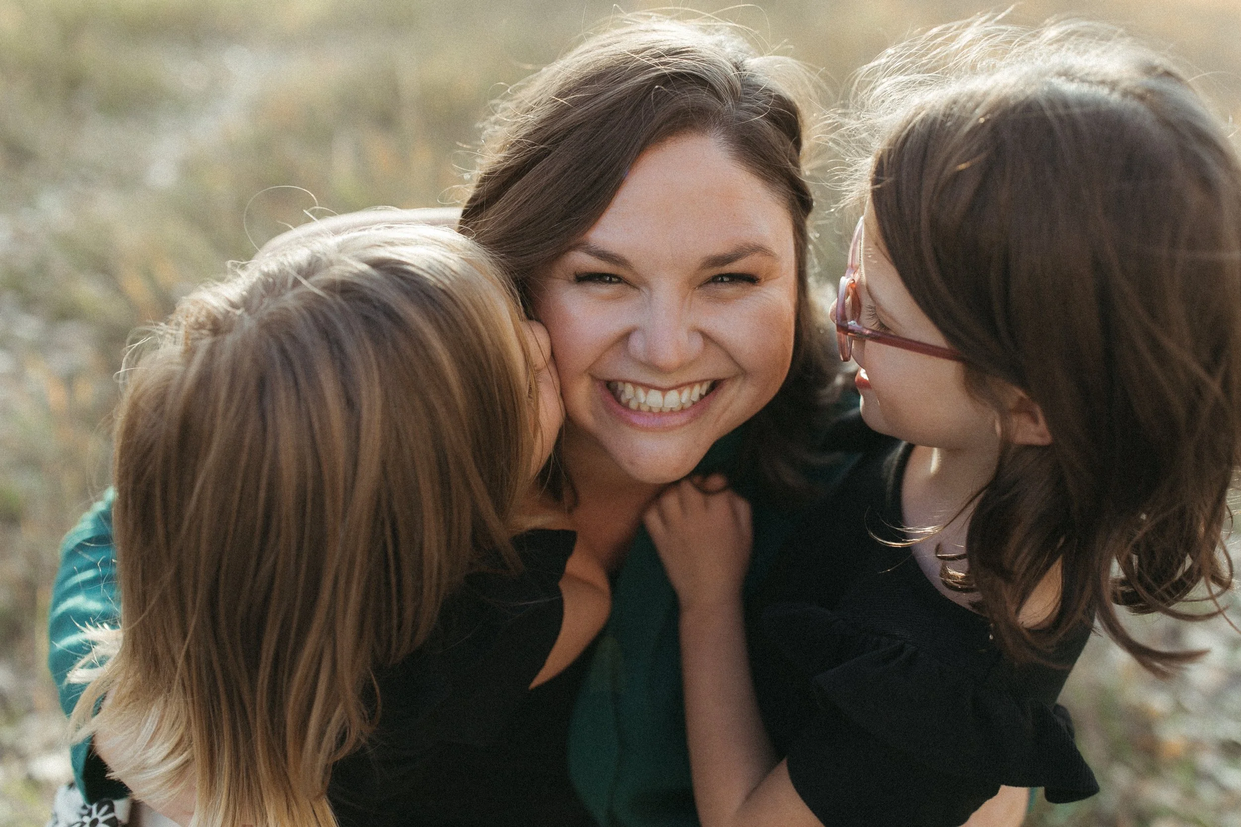 A group of women happily hugging outdoors on a sunny day.