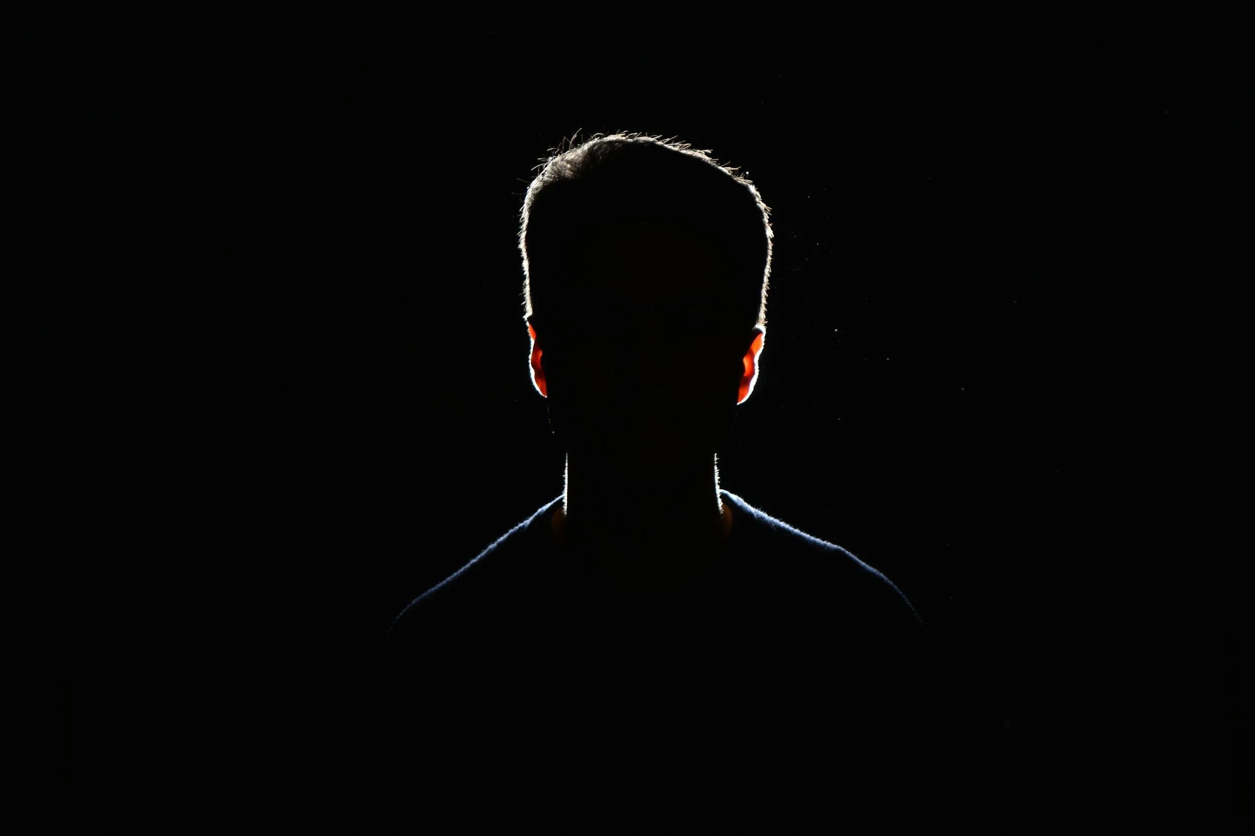 Silhouette of a person with a glowing outline against a black background, facing forward.