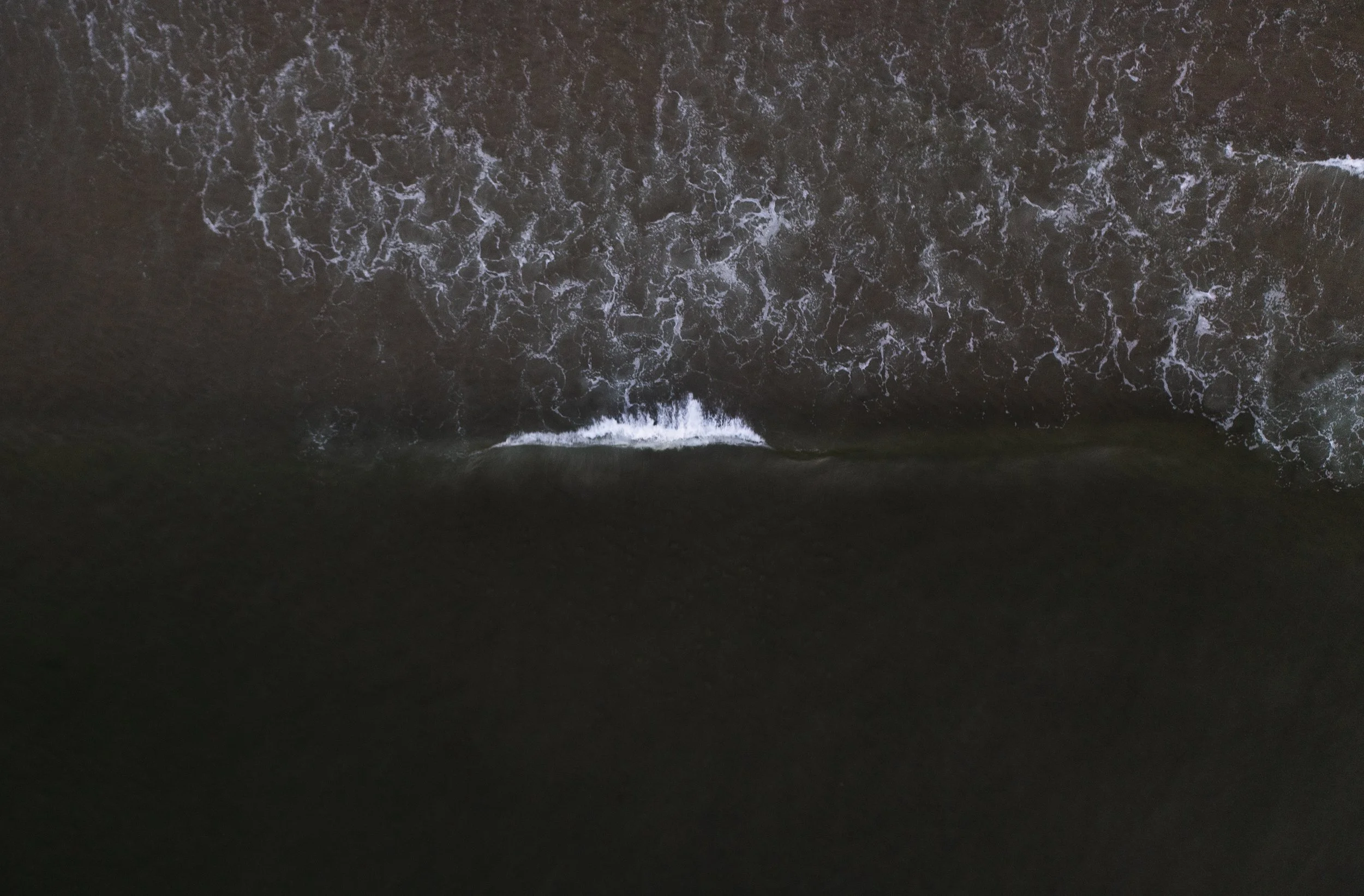 View of ocean water from above, showing waves and foam.