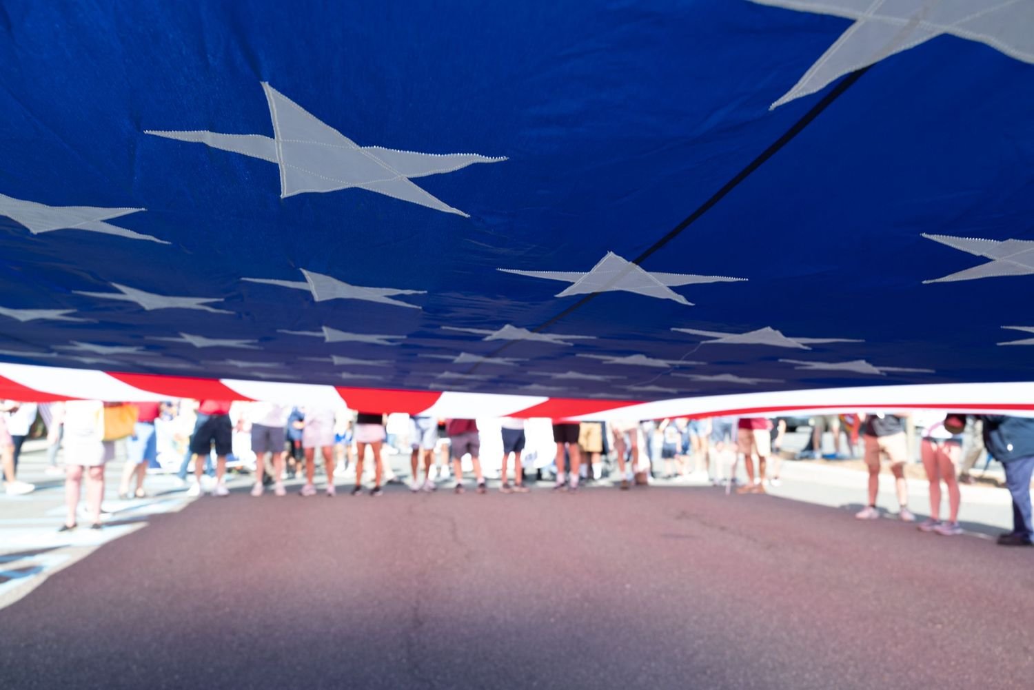 Large American flag being held by a crowd at a public demonstration.