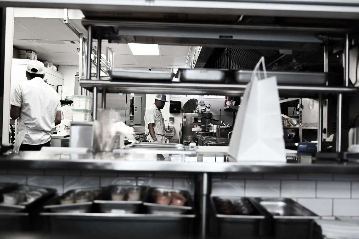 Chef working in commercial kitchen with kitchen equipment and stainless steel shelves.