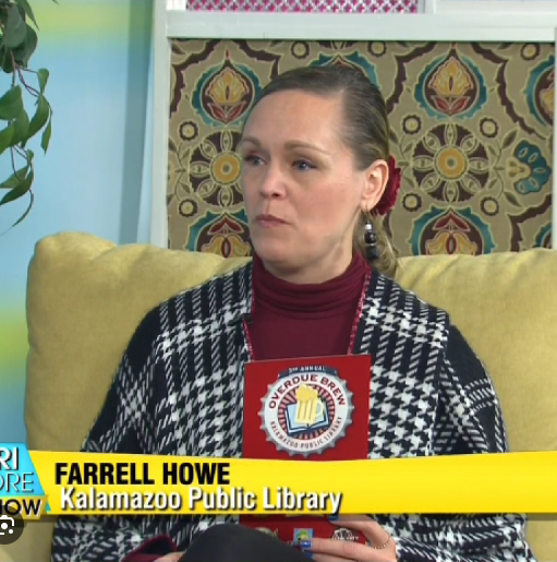Image of a woman holding a brochure that says Overdue Brew. She is interviewing about a library program. Links o a news story.
