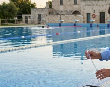 Una mano che tiene un elemento di misurazione vicino a una piscina all'aperto.