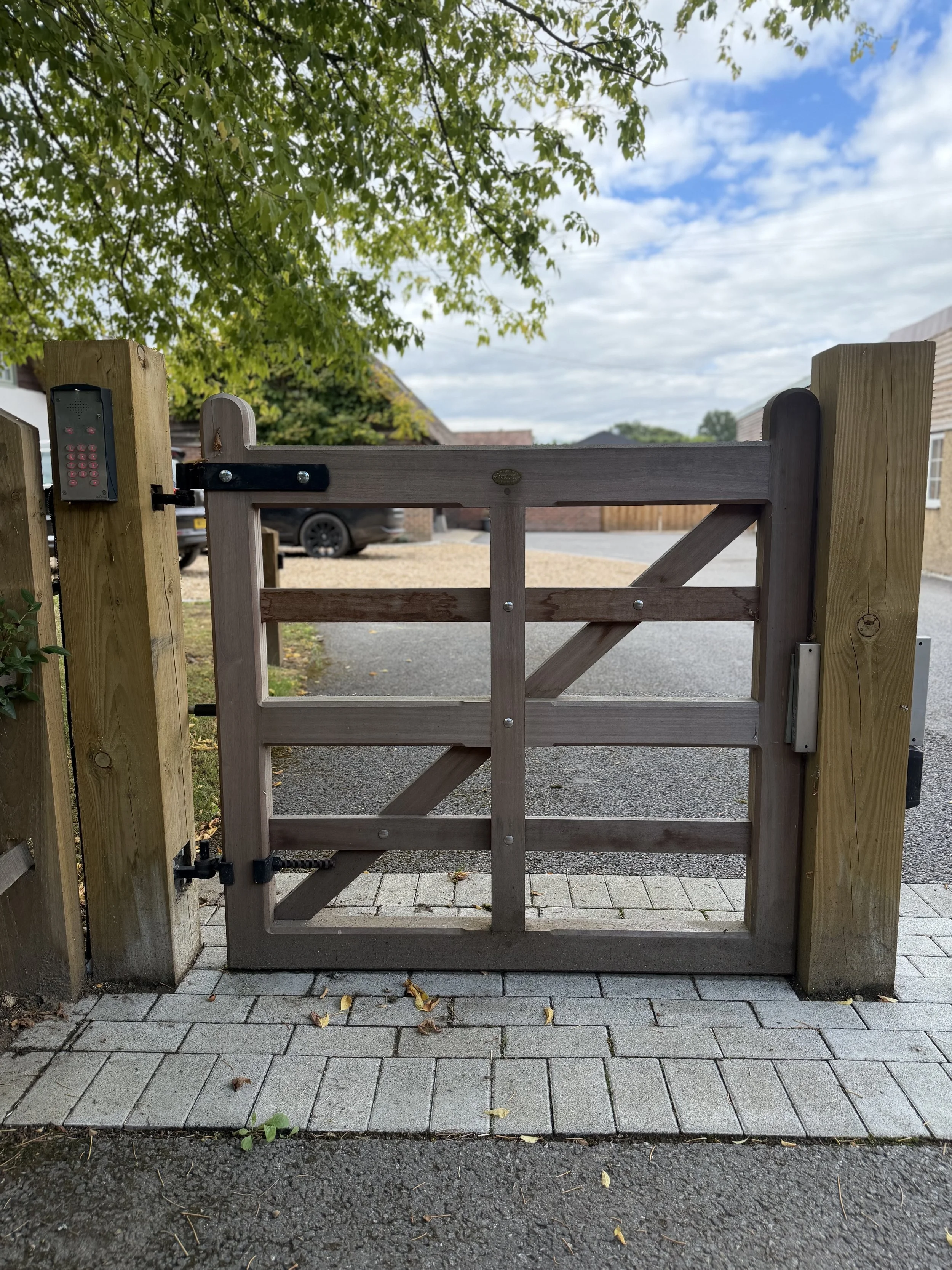 Timber pedestrian gate hung between timber posts beside a paved path