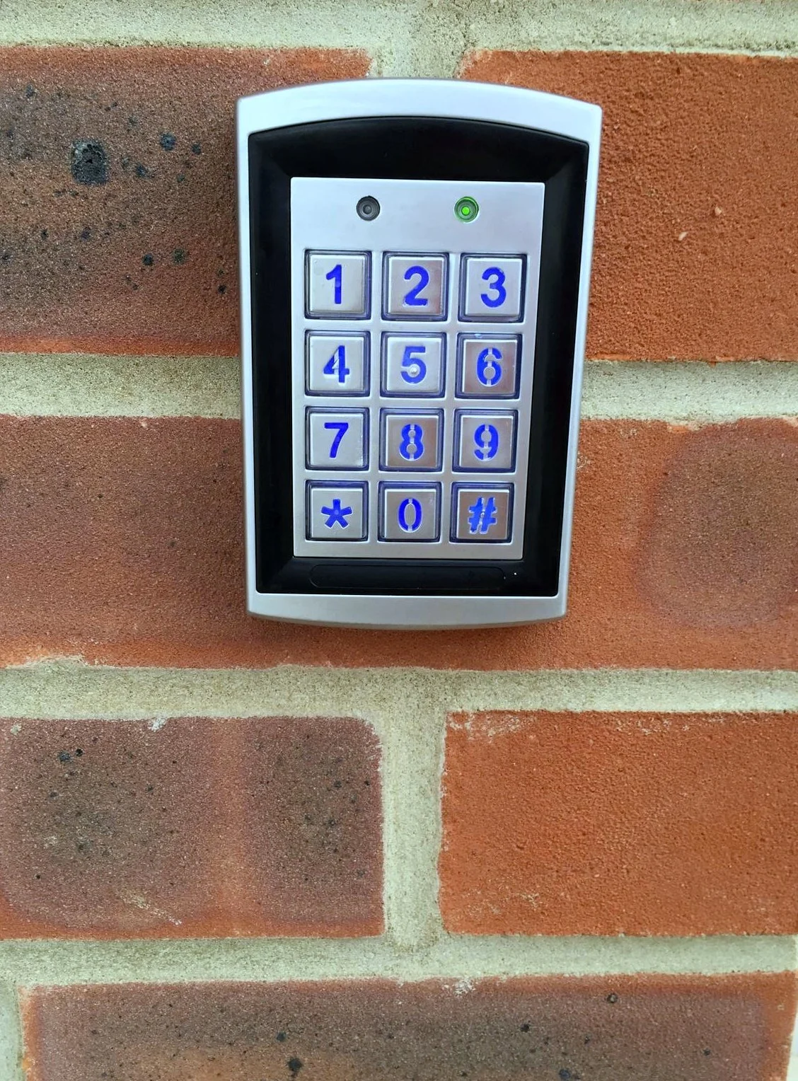 Illuminated access keypad on a brick wall