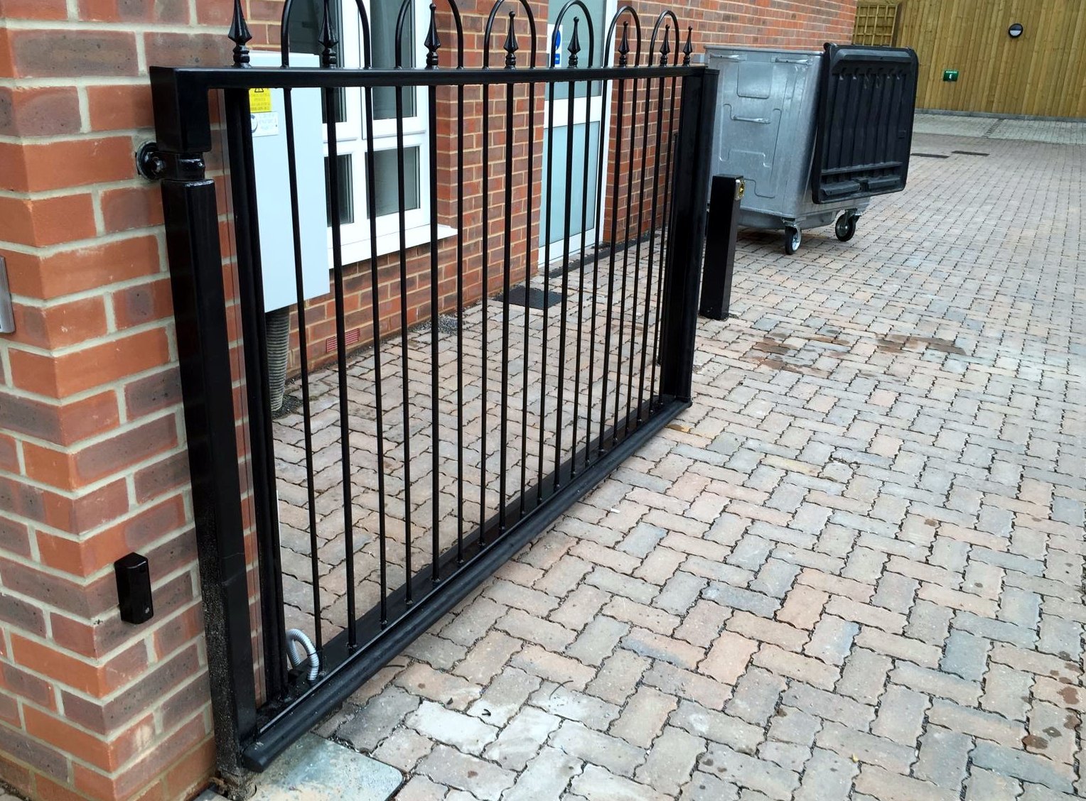 Swing gate on a brick pier across a paved path