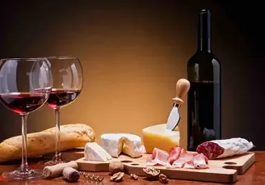 A sharing board with cheeses, cured meats, bread and red wine