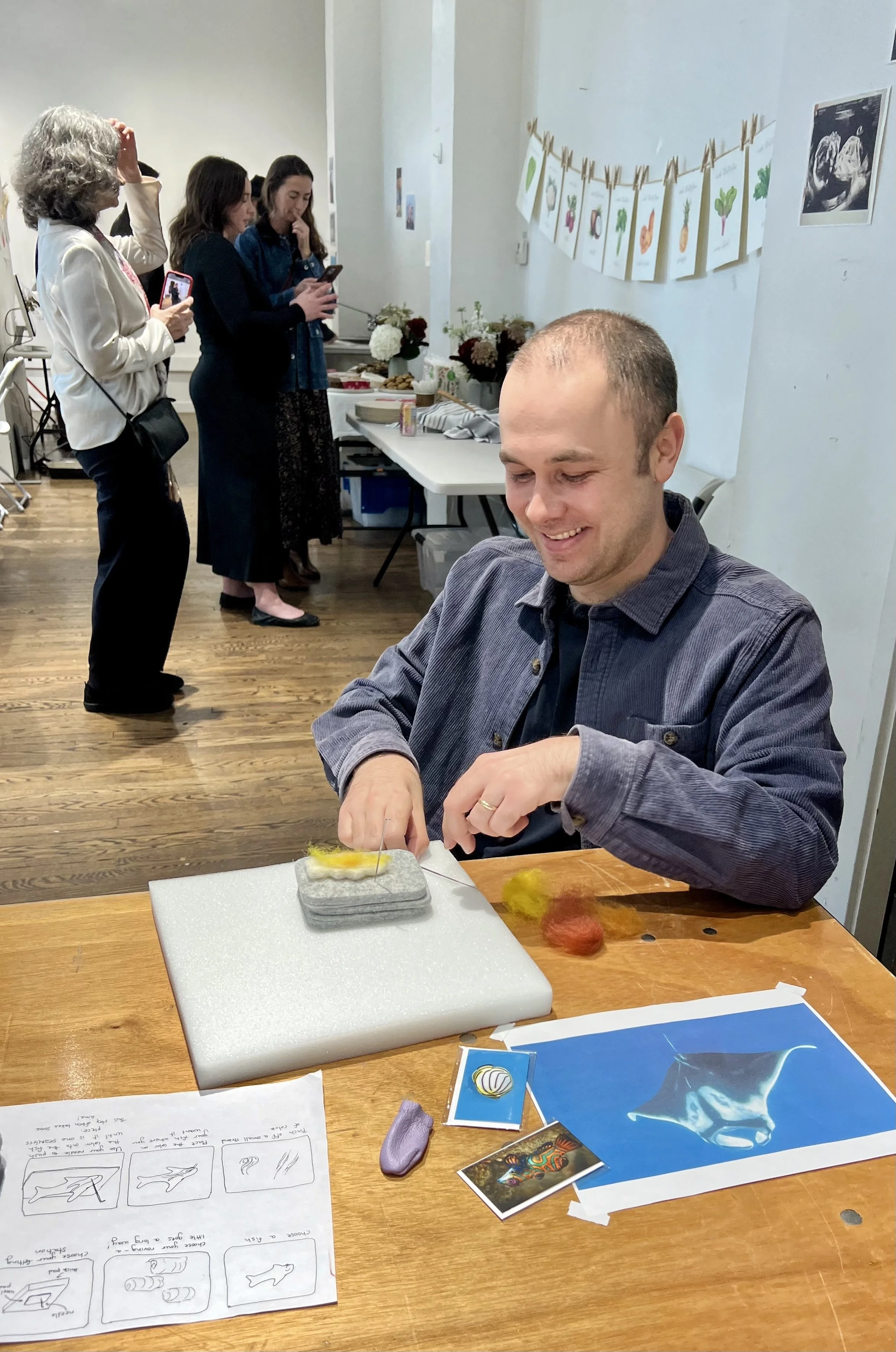 a happy father-to-be works on his felted fish for his baby's mobile