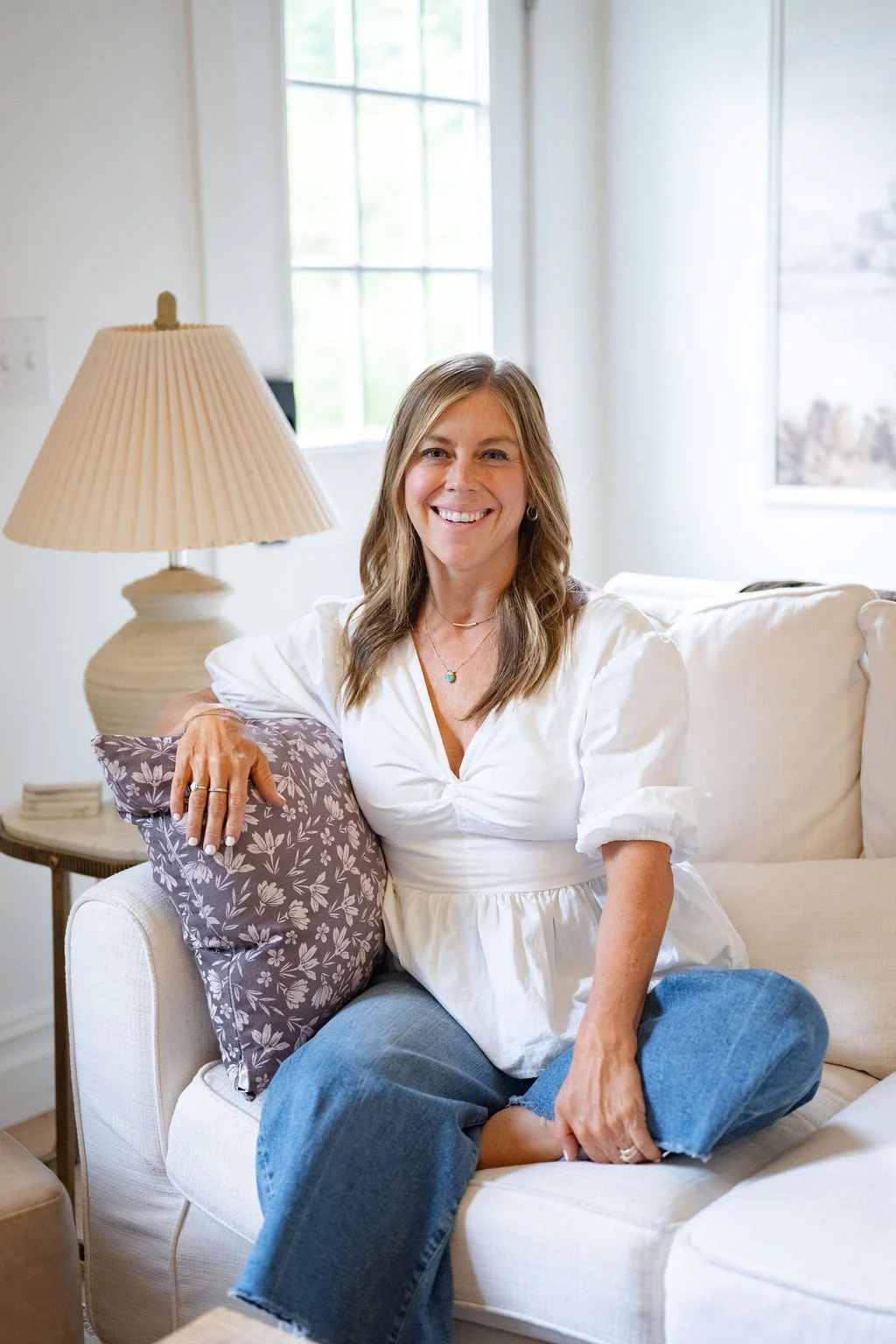 Smiling client relaxing on a sofa after a concierge botox appointment in Wilmington, NC
