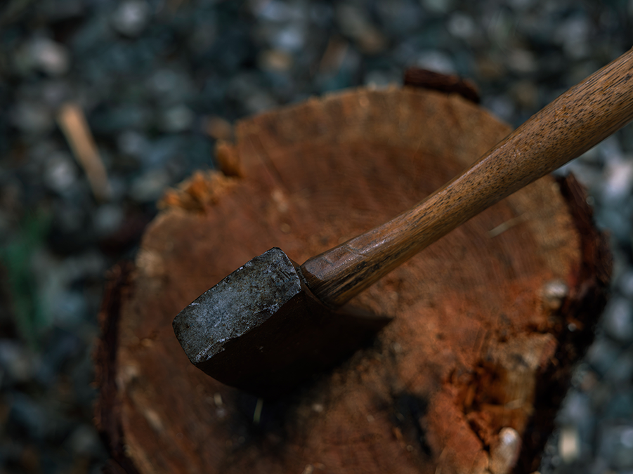 A hammer resting on a cut tree trunk outdoors