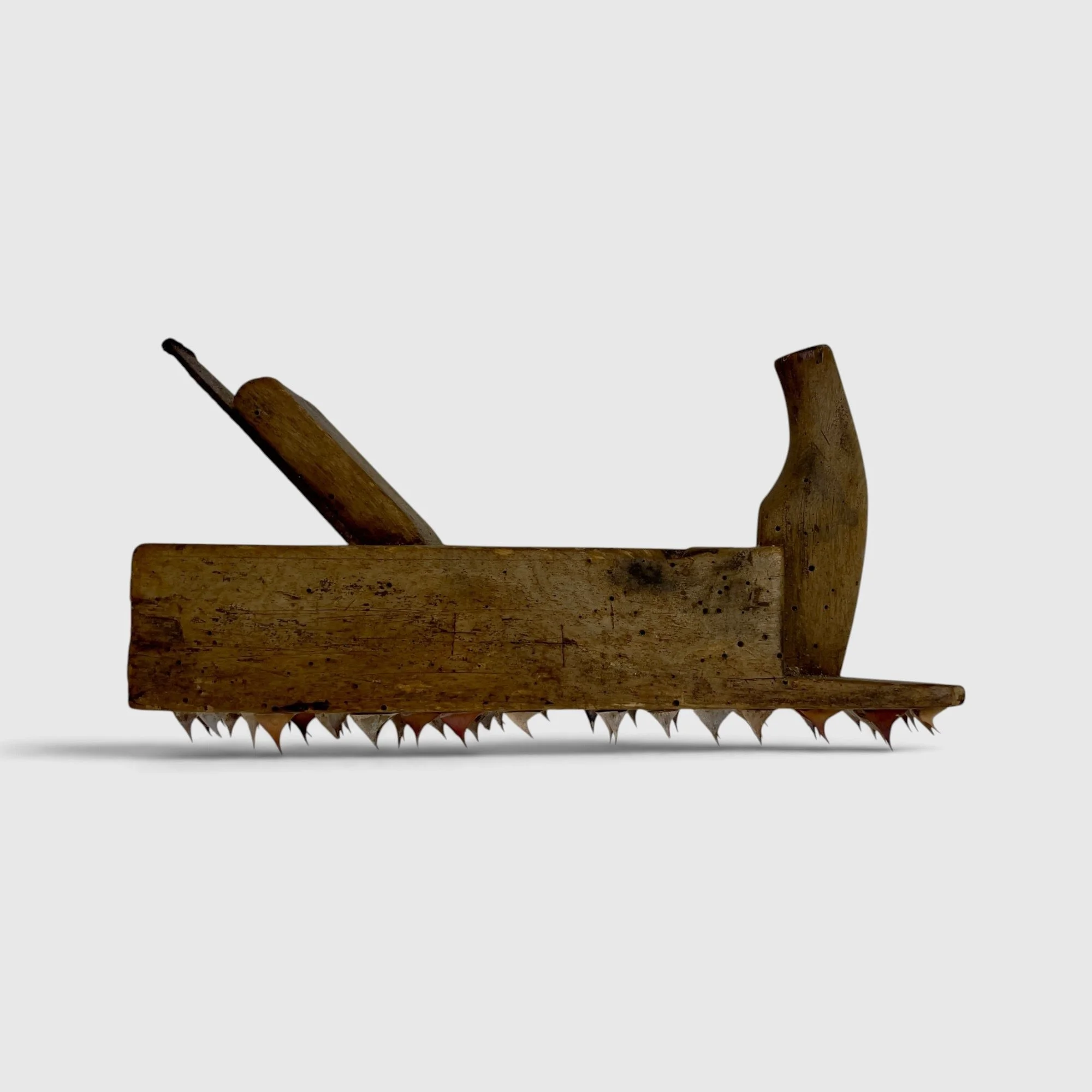 Working Object 04, 2025: An old wooden hand plane with a row of rose thorns attached beneath its base.