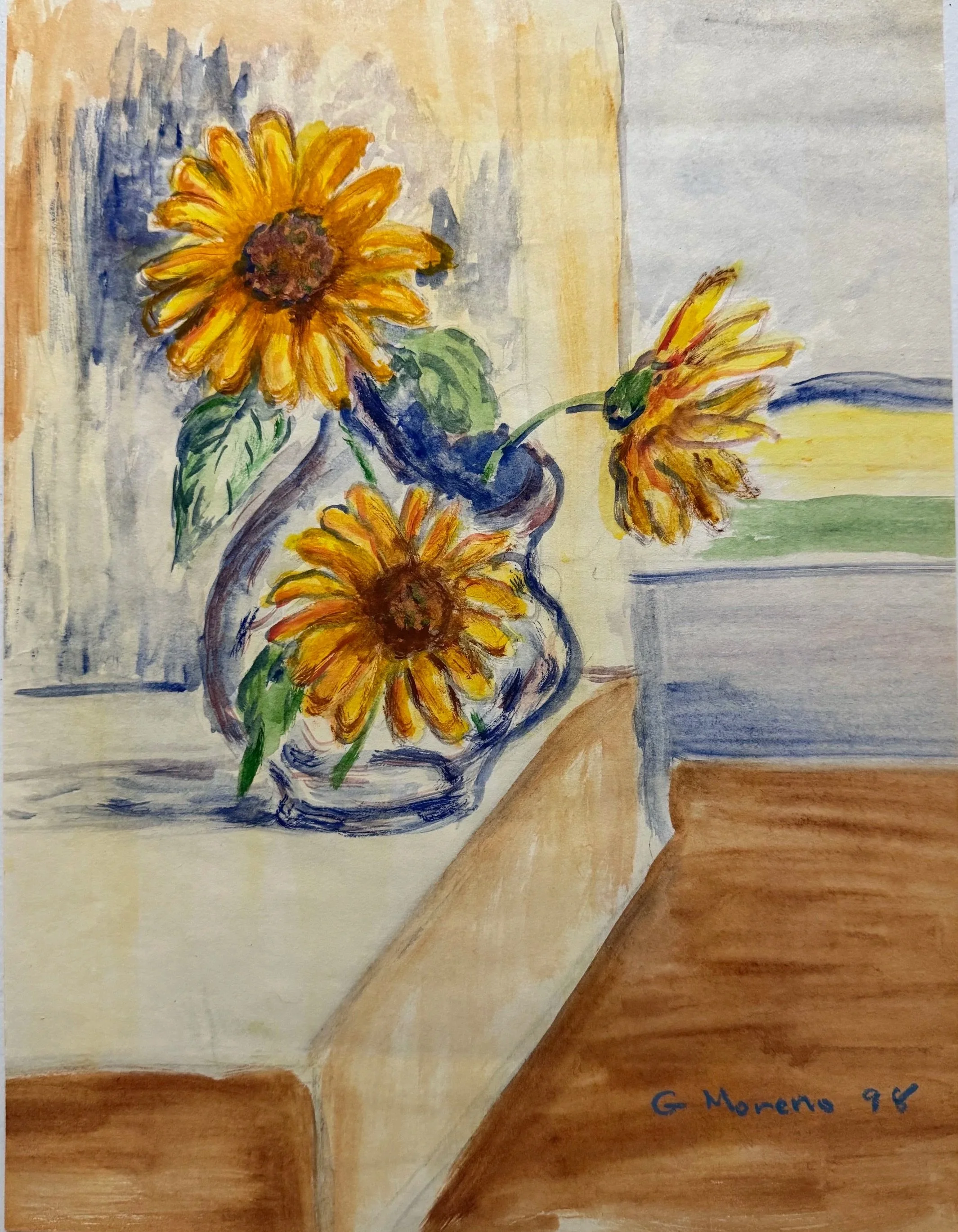 Watercolor painting of three yellow flowers in a vase placed on a wooden table. The background features abstract hues of gray, blue, and beige, with the artist's signature 'G. Moreno 96' in blue at the bottom right corner.