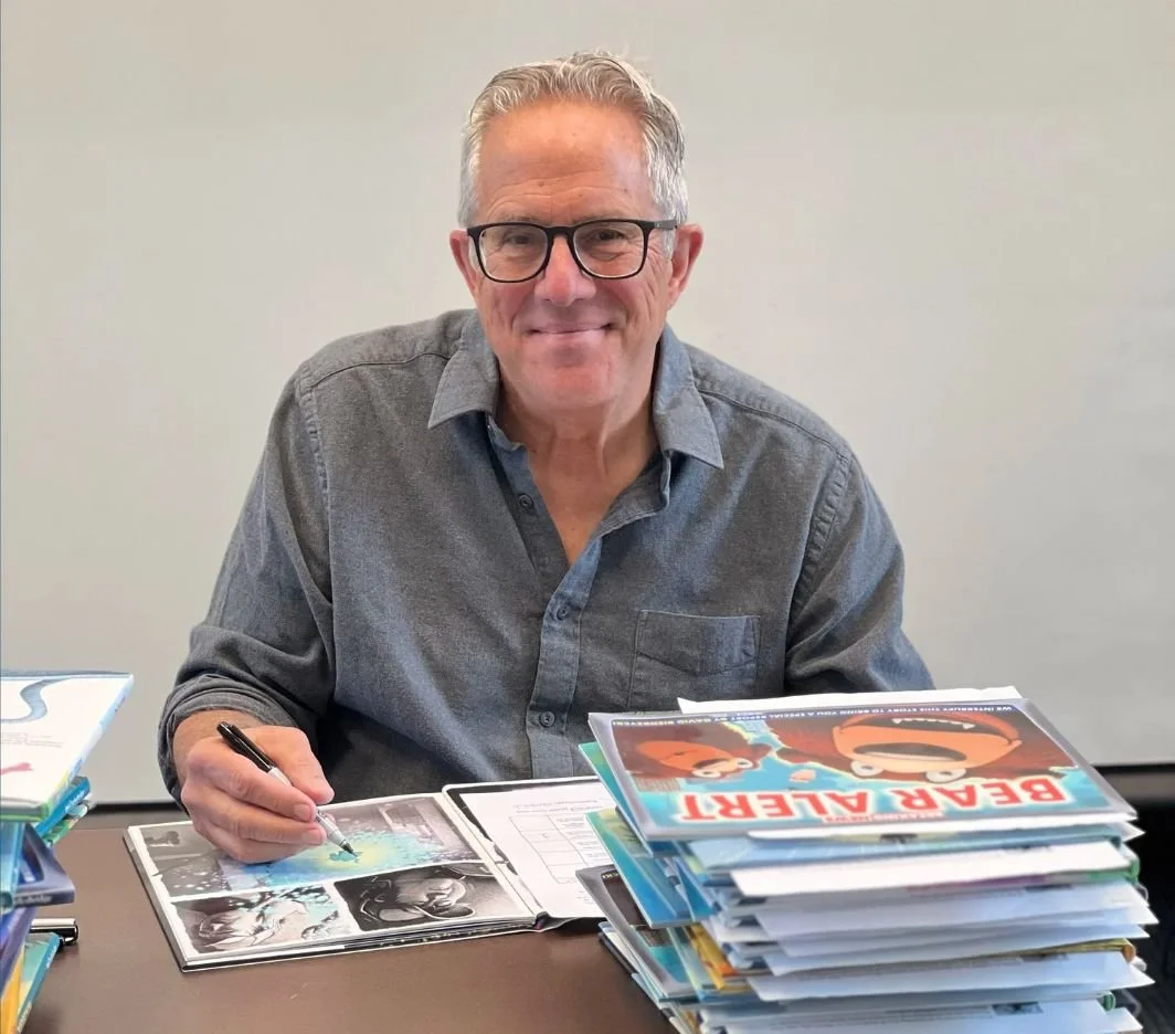 David Biedrzycki autographing books beside a stack of his picture books.