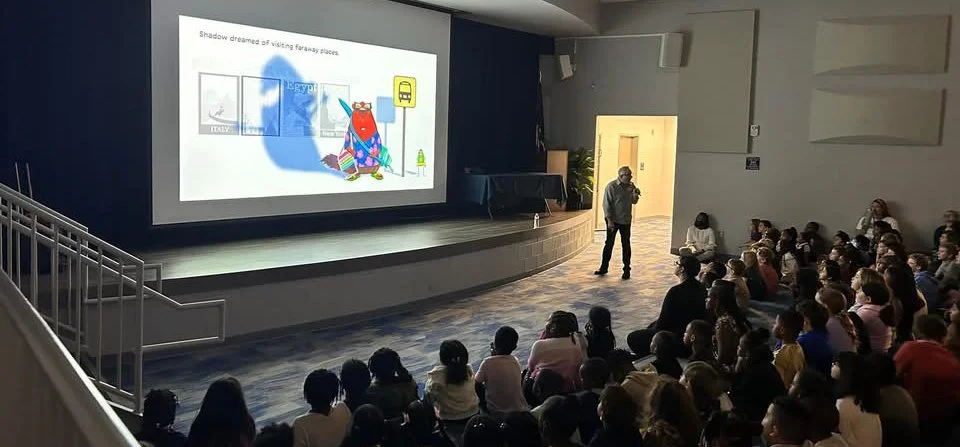 David Biedrzycki speaking to students during a school visit presentation in an auditorium.