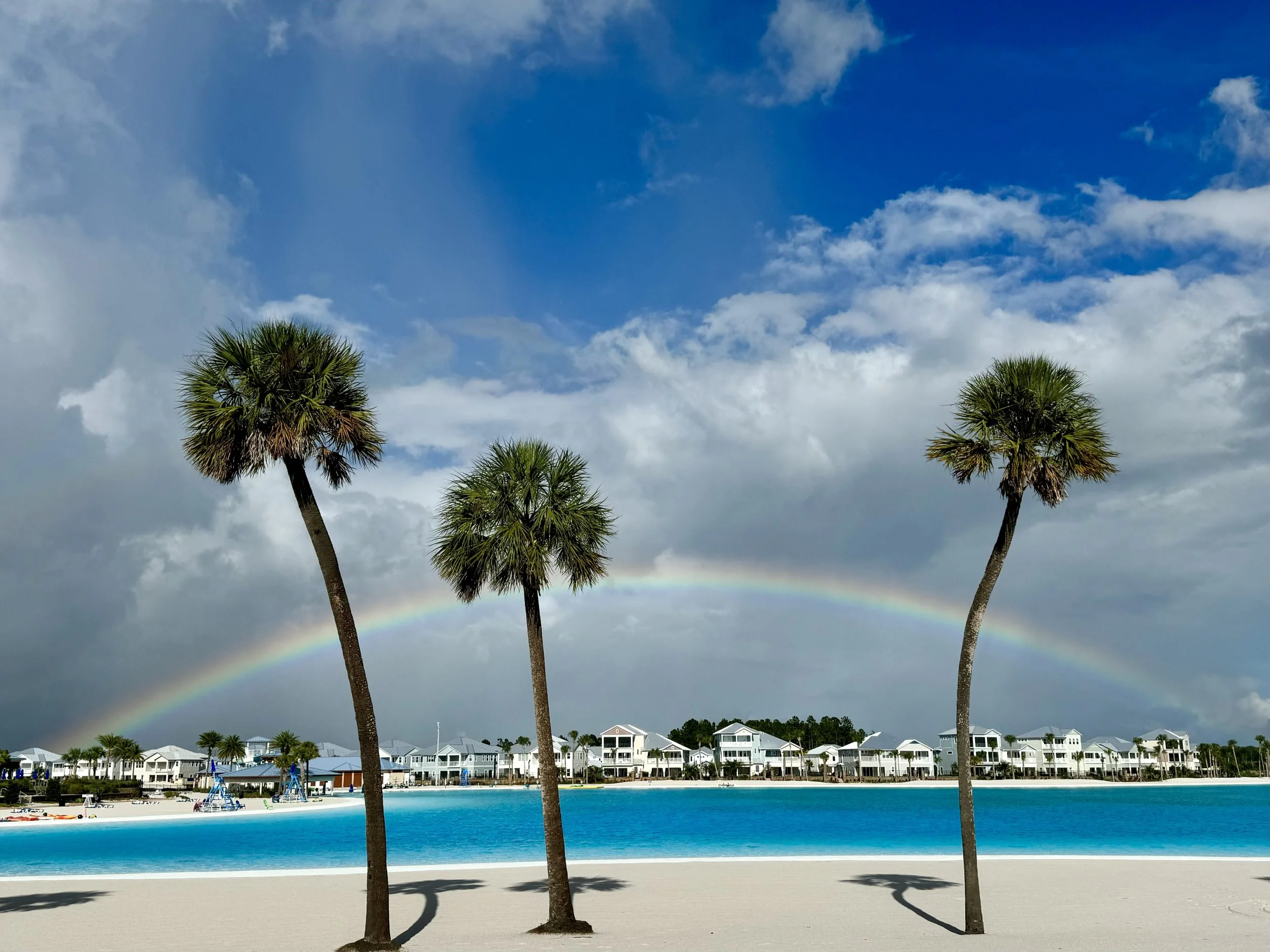 Rainbow over Beachwalk Crystal Lagoon with palm trees and lagoon-front homes