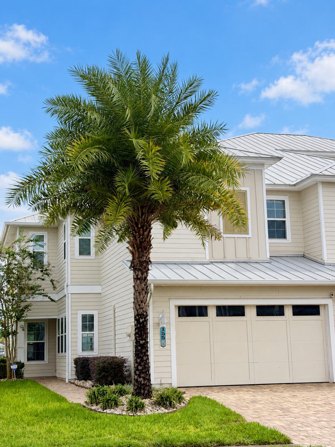 Front exterior of 155 Rum Runner Way in Beachwalk with palm tree and two-car garage