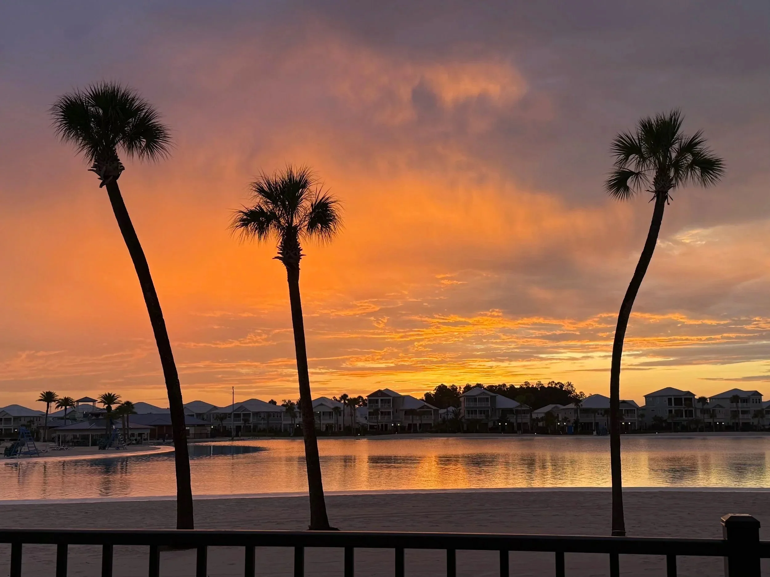 Sunset over Beachwalk Crystal Lagoon with palm trees, featured alongside the Wall Street Journal story about 155 Rum Runner Way
