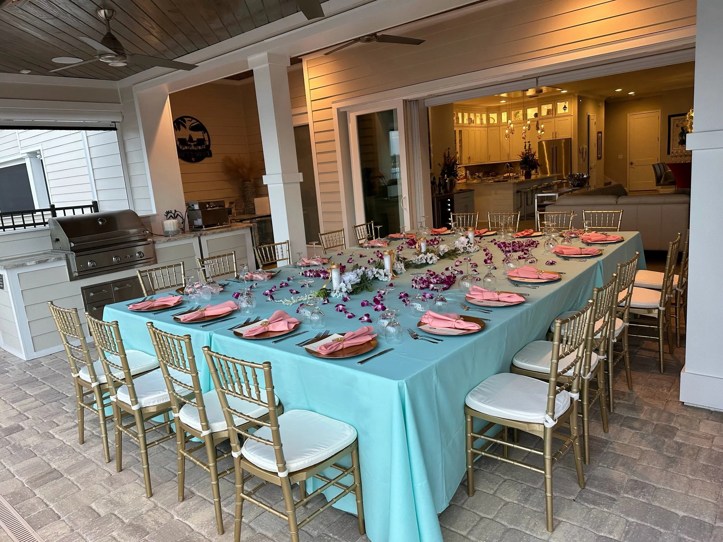 Expanded lagoon-front lanai set for entertaining with summer kitchen and custom wood herringbone ceiling