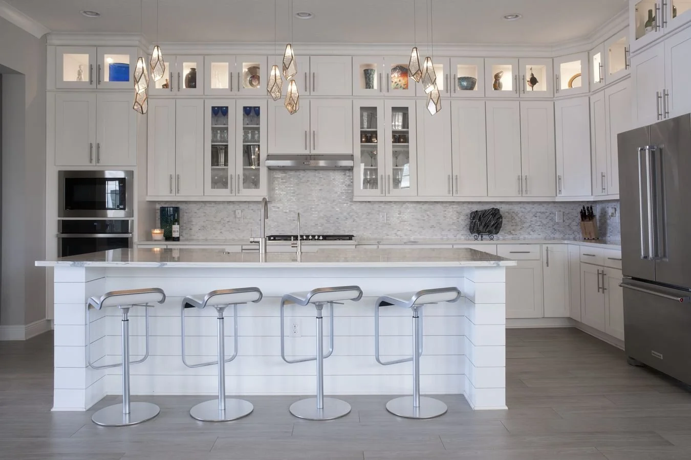 Open-concept kitchen with large island, white cabinetry and pendant lighting at 155 Rum Runner Way