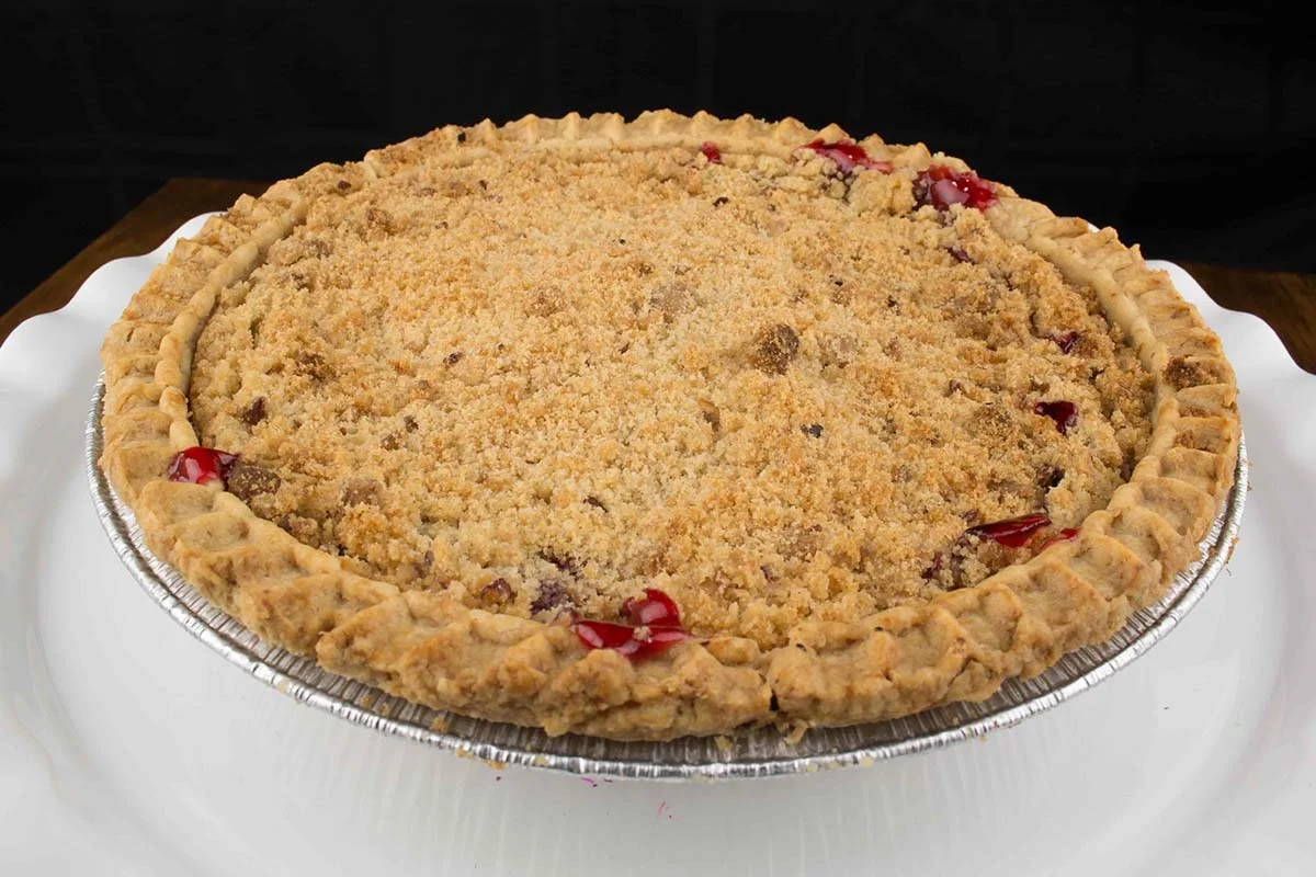 Homemade cherry crumb pie with a golden streusel topping in a foil pie pan