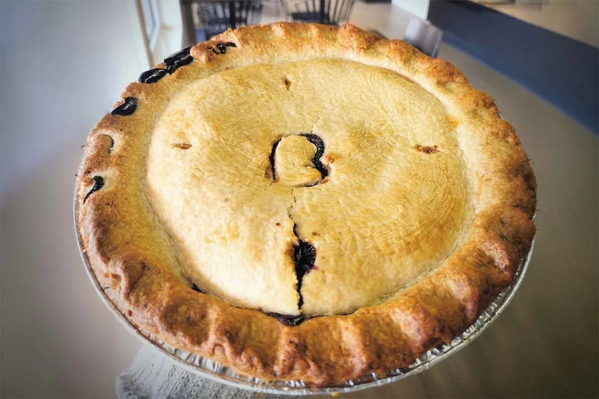 Golden-brown homemade fruit pie with a decorative heart-shaped vent in the crust, served in a foil pie pan.