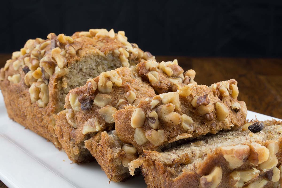 Sliced walnut banana bread loaf on a white plate