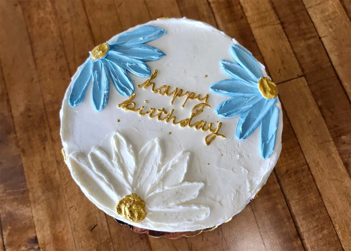 White happy birthday cake with blue flowers.