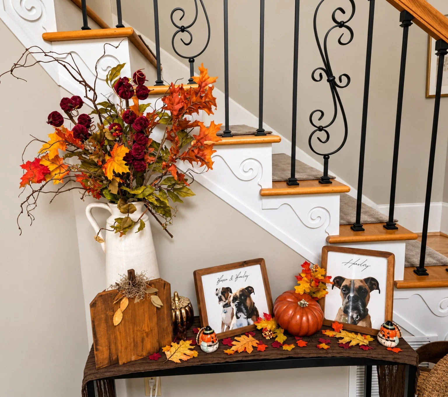 Fall console by staircase styled with autumn florals, pumpkins, framed dog portraits, and seasonal accents.