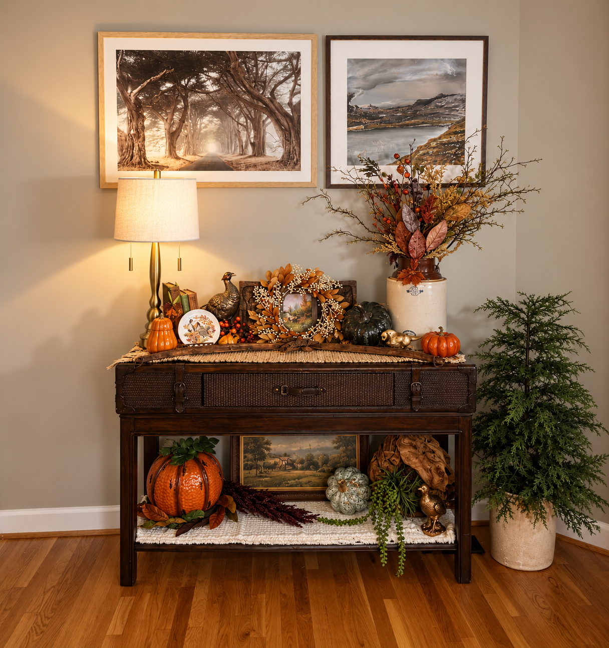Fall console styled with pumpkins, autumn greenery, framed art, warm lighting, and layered seasonal décor.