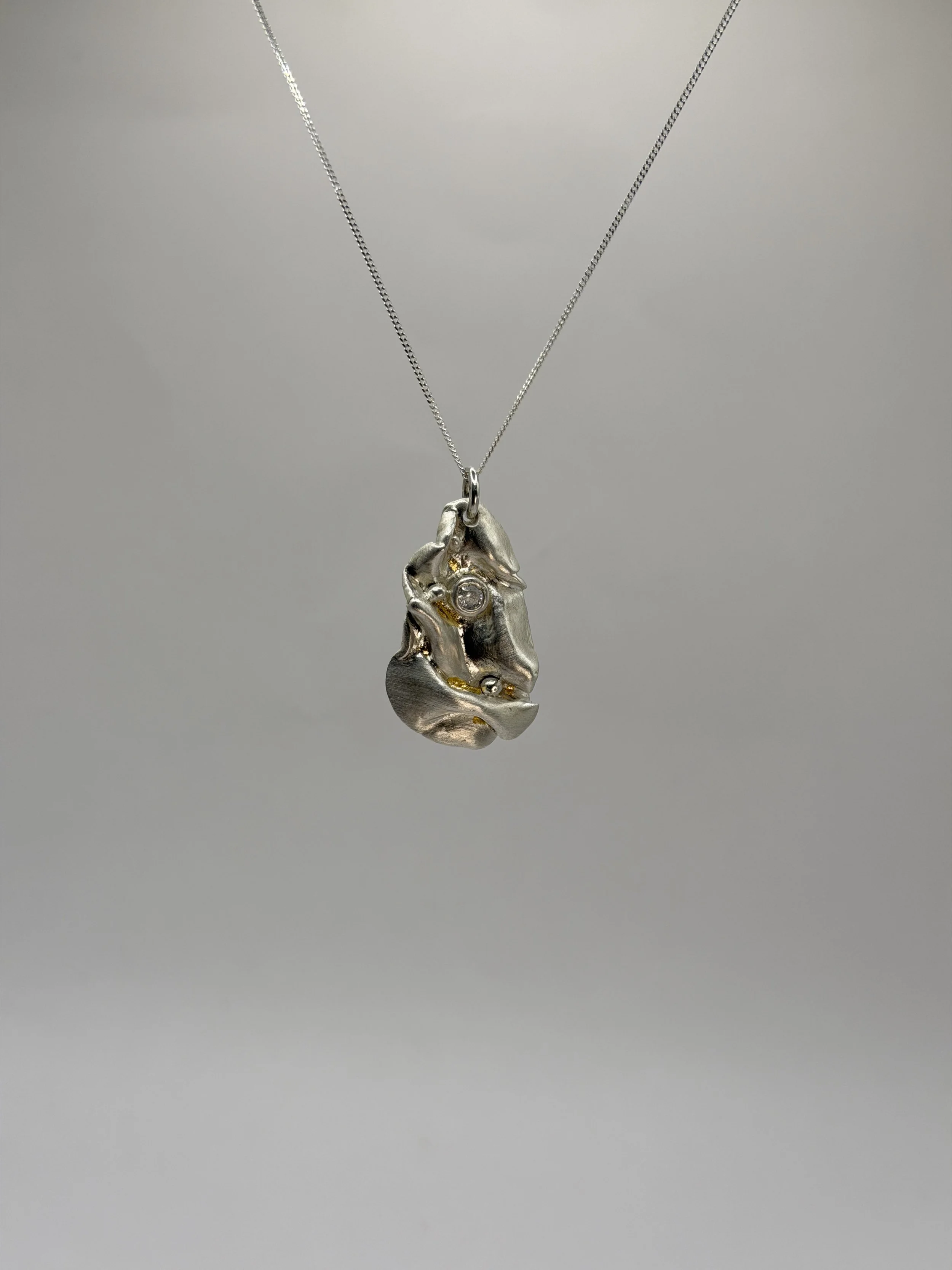 Sculptural fine silver pendant with organic flowing forms and keum-boo gold detailing, handmade by Avila Jewellery Designs.