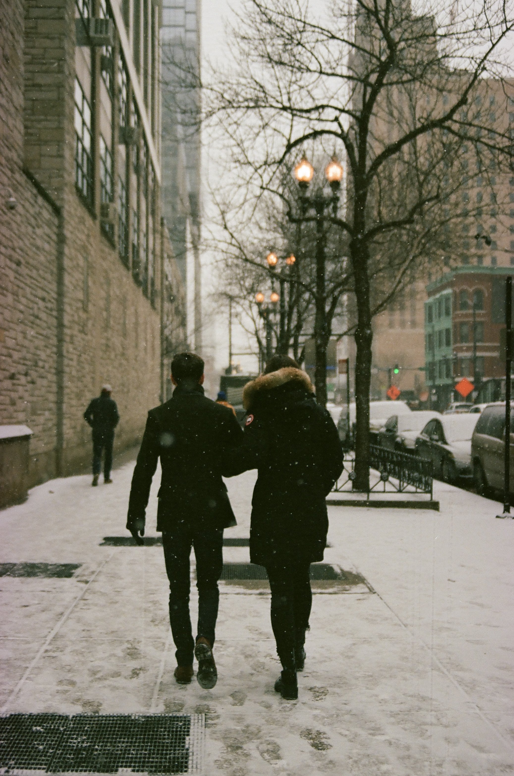 Couple walking arm-in-arm through a snow city street in winter in Chicago. 