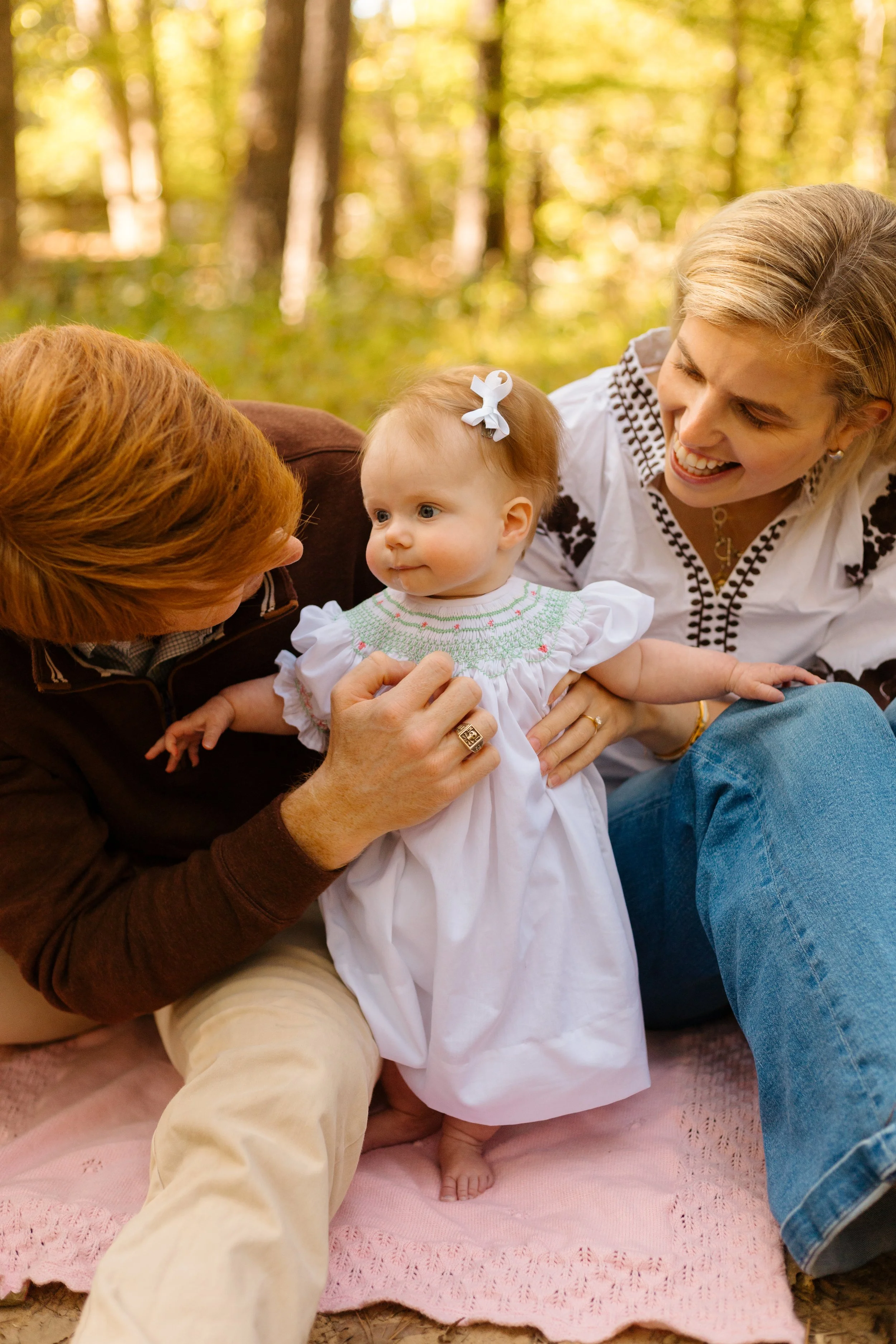A mother, father and baby on a fall picnic blanket during a family photo session.