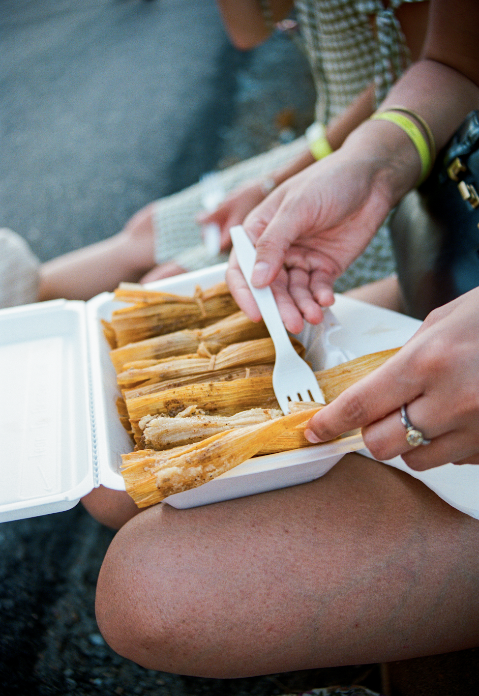 Person holding a styrofoam container of tamales, using a plastic fork to eat. Take in the Mississippi Delta. 