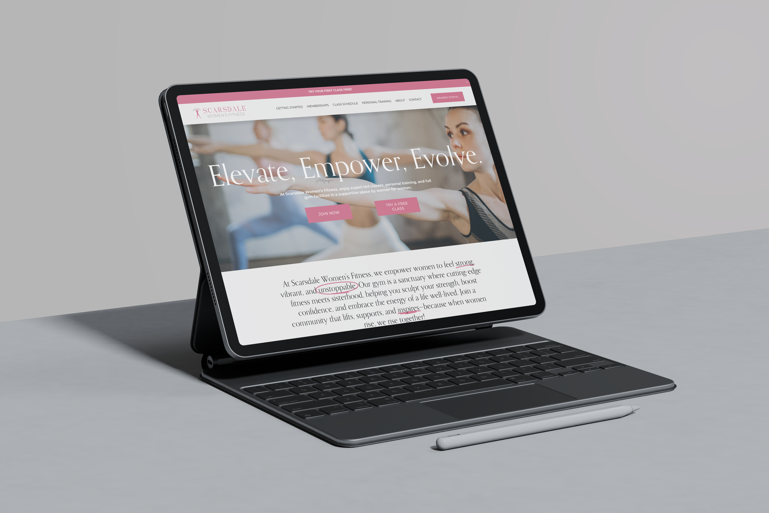 An iPad Pro with a keyboard attachment sitting on a gray surface. The screen displays a website titled 'Scarsdale Women's Fitness' with the slogan 'Elevate, Empower, Evolve' and a background image of women exercising. A stylus pen rests beside it.