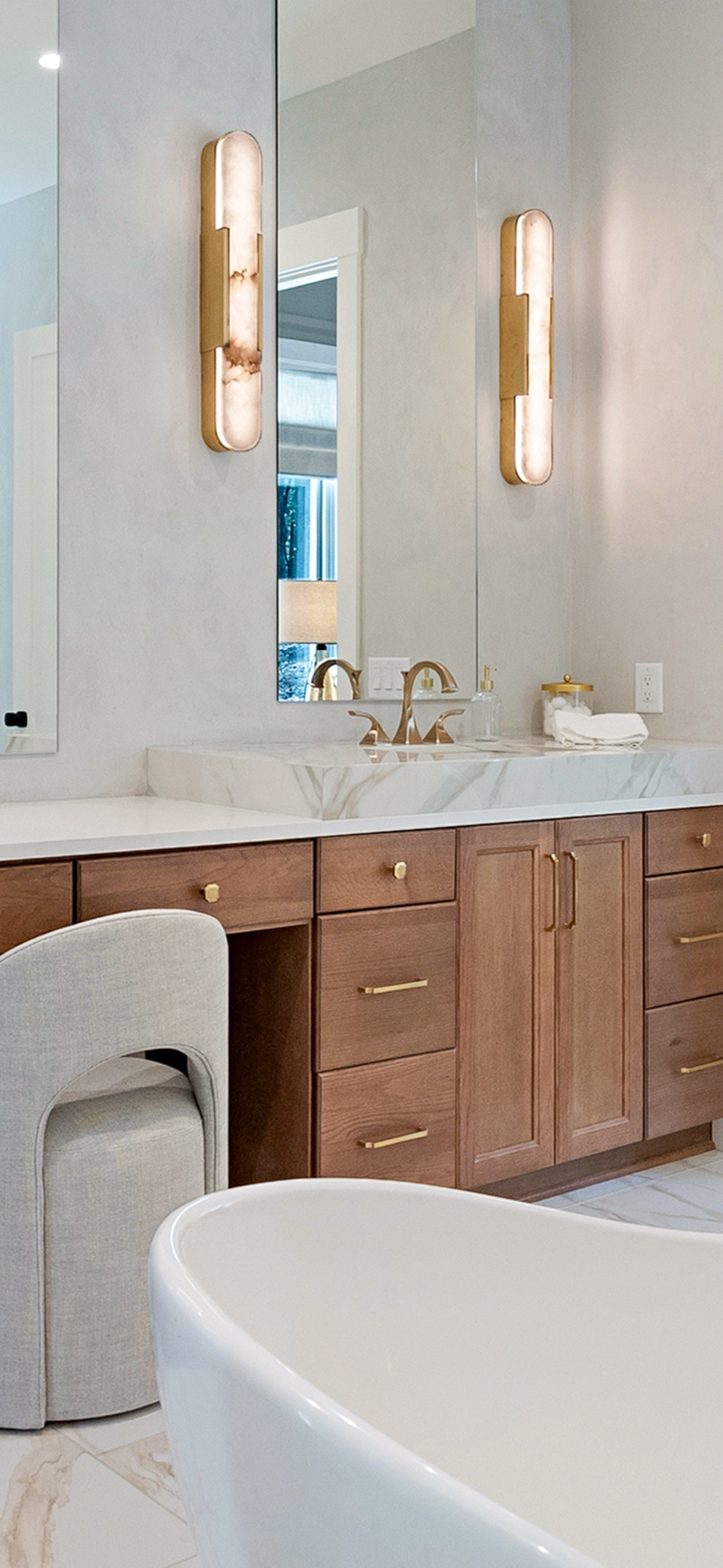 Modern bathroom with wooden vanity, marble countertop, rectangular mirror, and decorative wall sconces