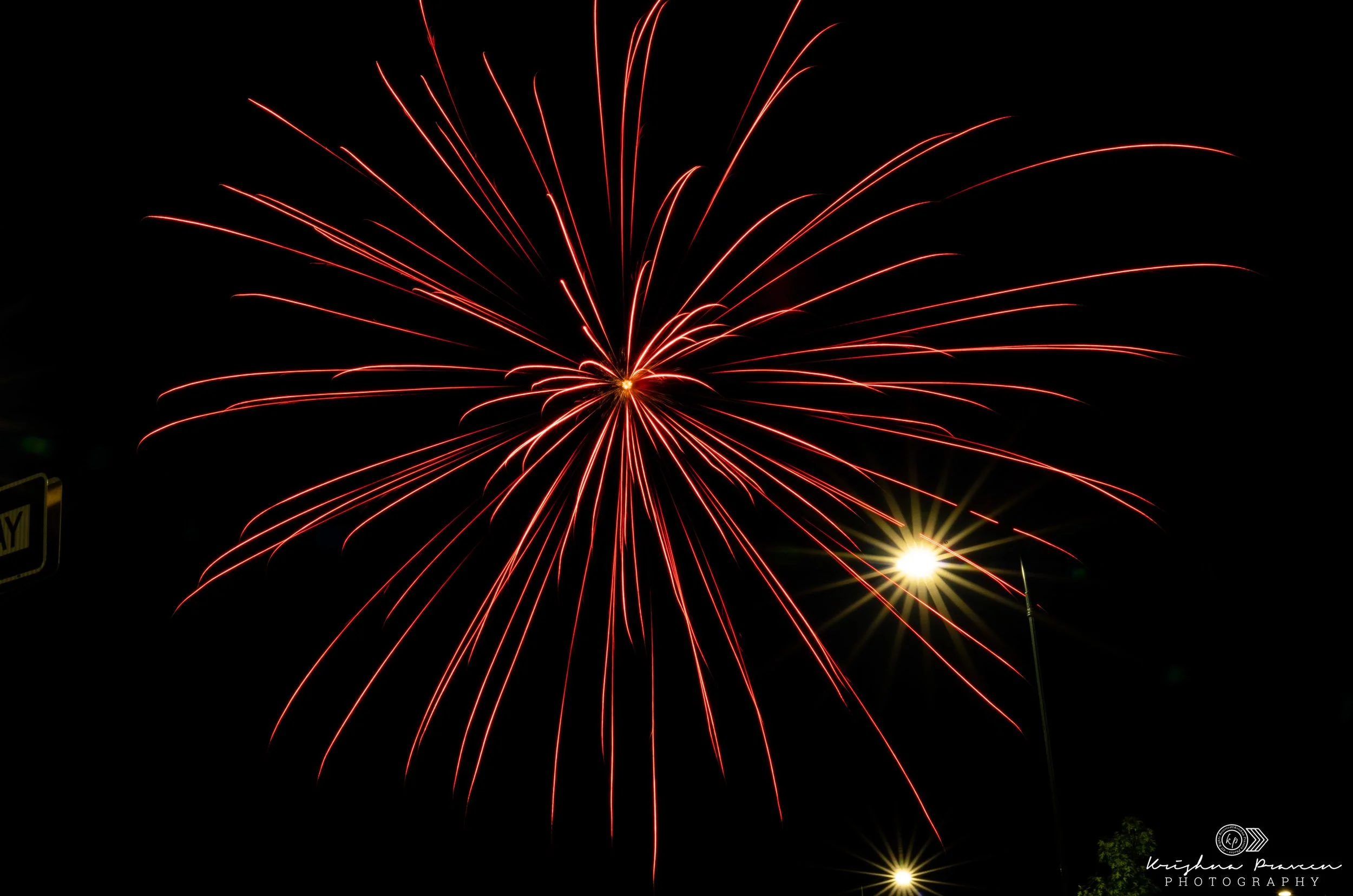 Red fireworks exploding against a black night sky with bright streaks radiating outward.
