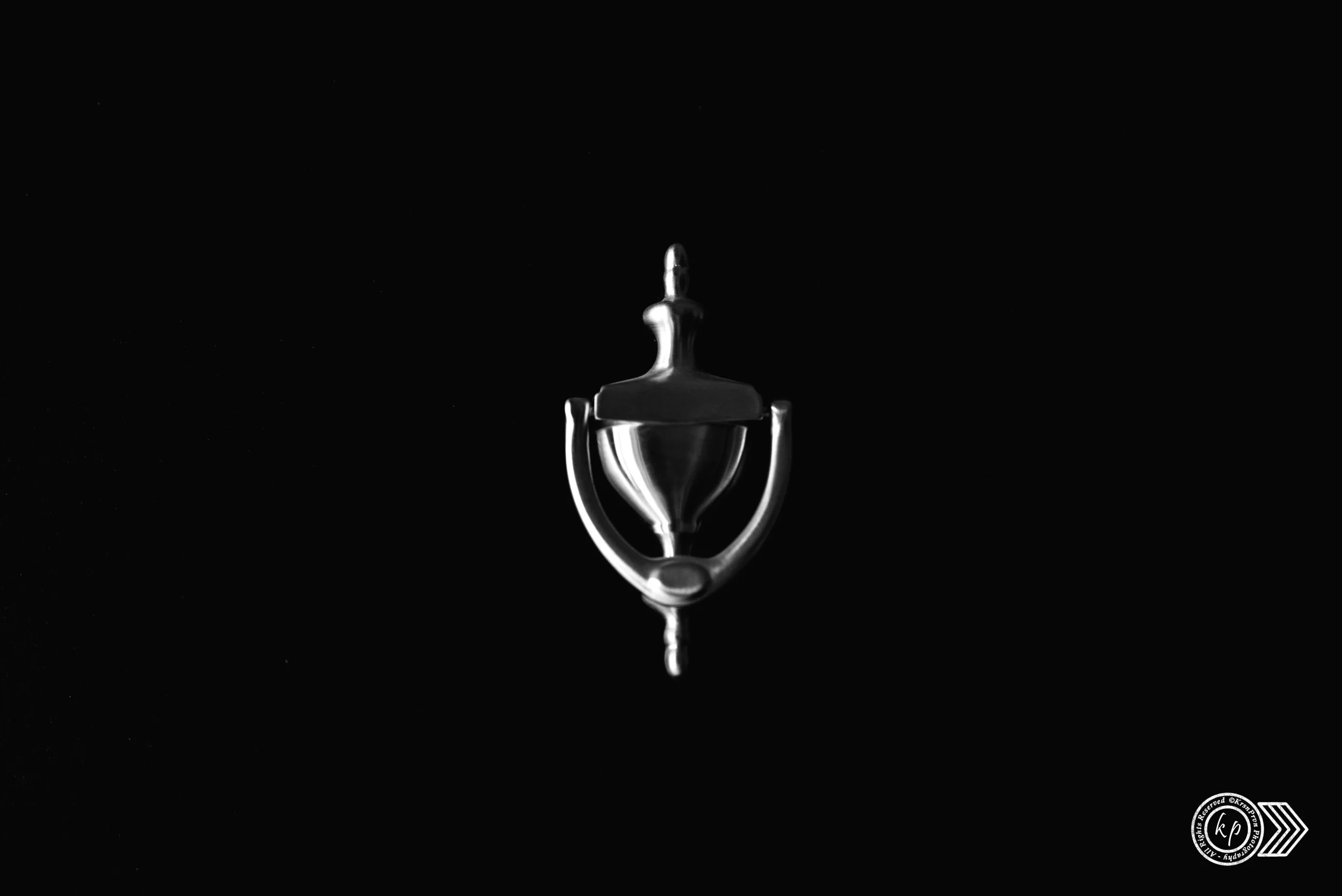 Close-up of a metallic hook hanging against a black background.