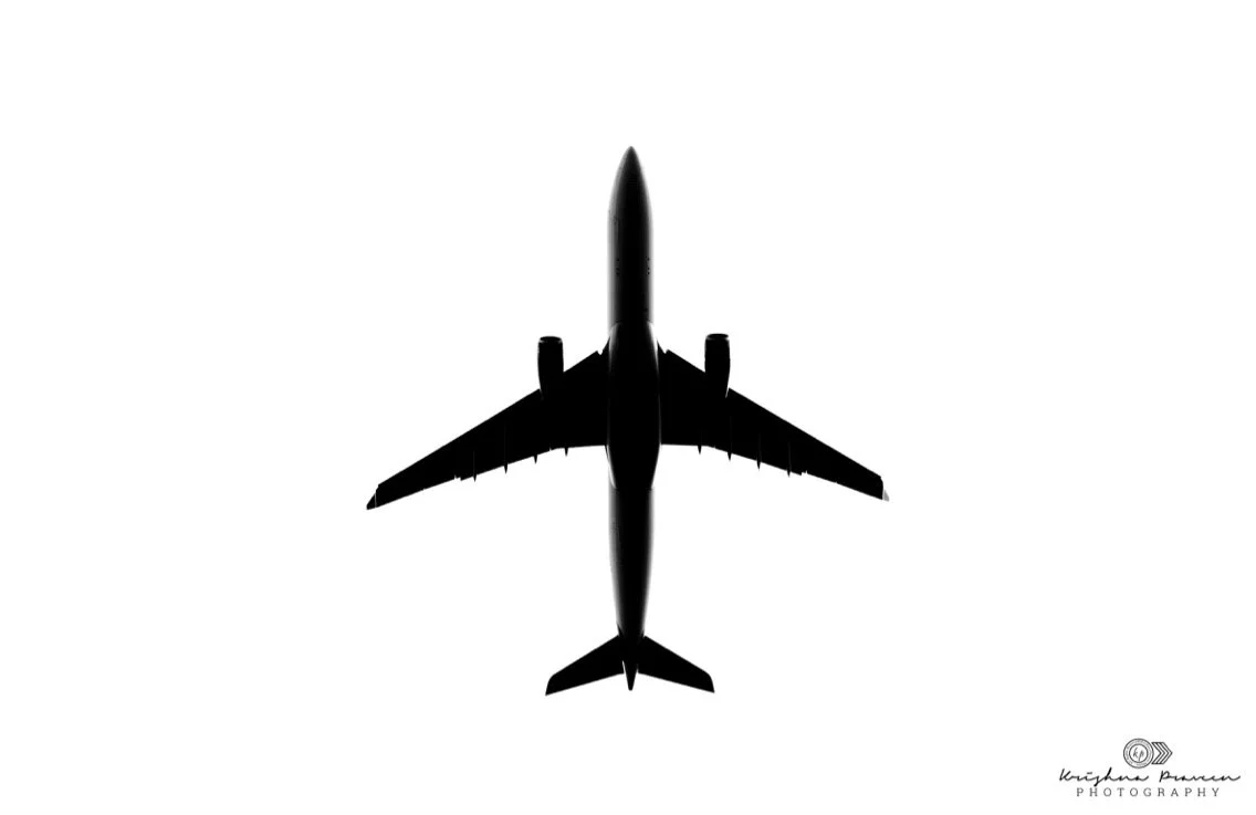 Silhouette of a commercial airplane viewed from above against a white background.