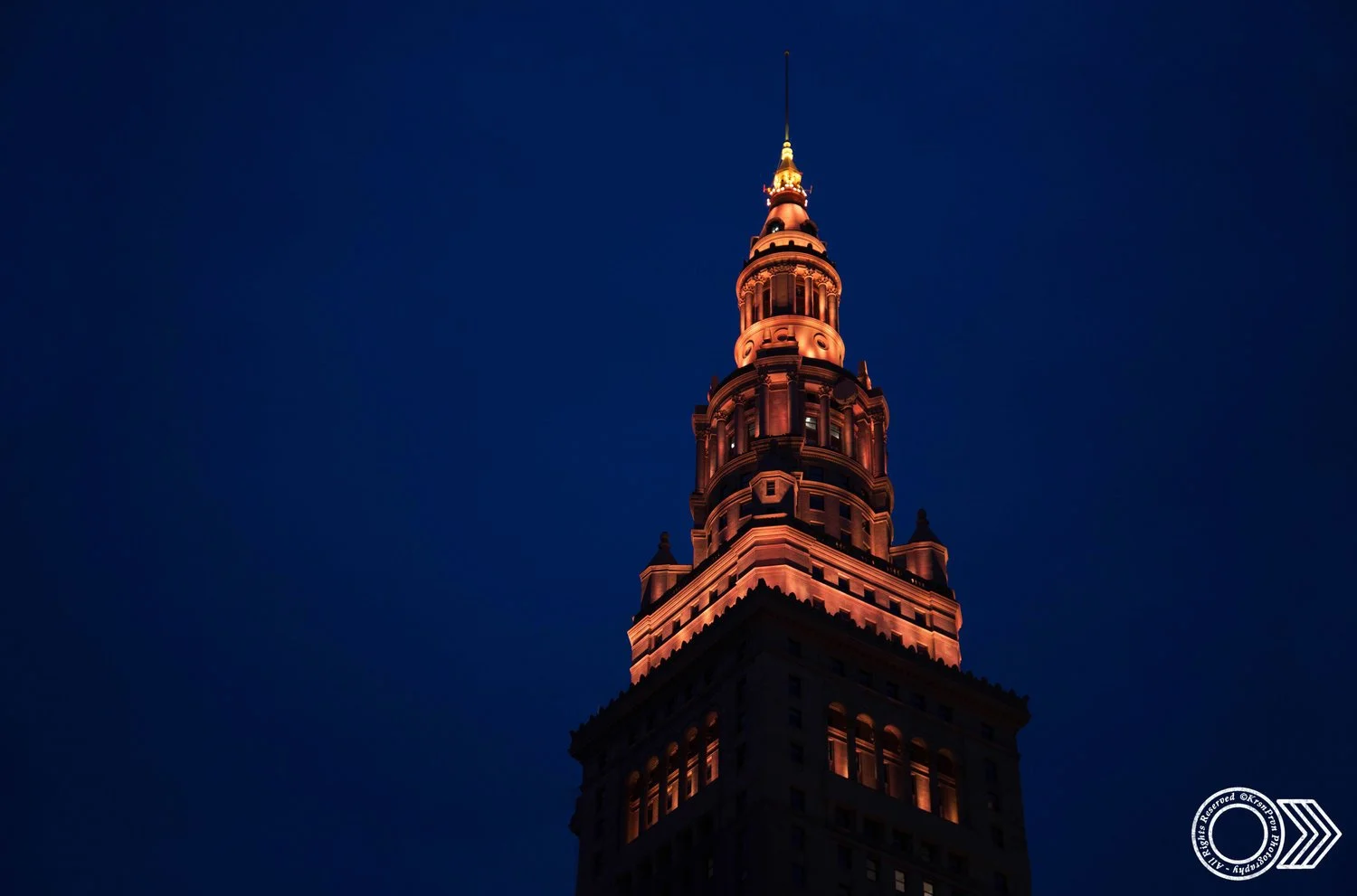 A tall, illuminated historic tower at night with a dark blue sky in the background.