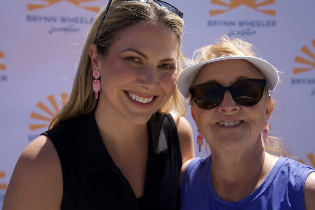 Two women smiling in front of a backdrop with the logo and text 'Beyond Wheeling Foundation'.
