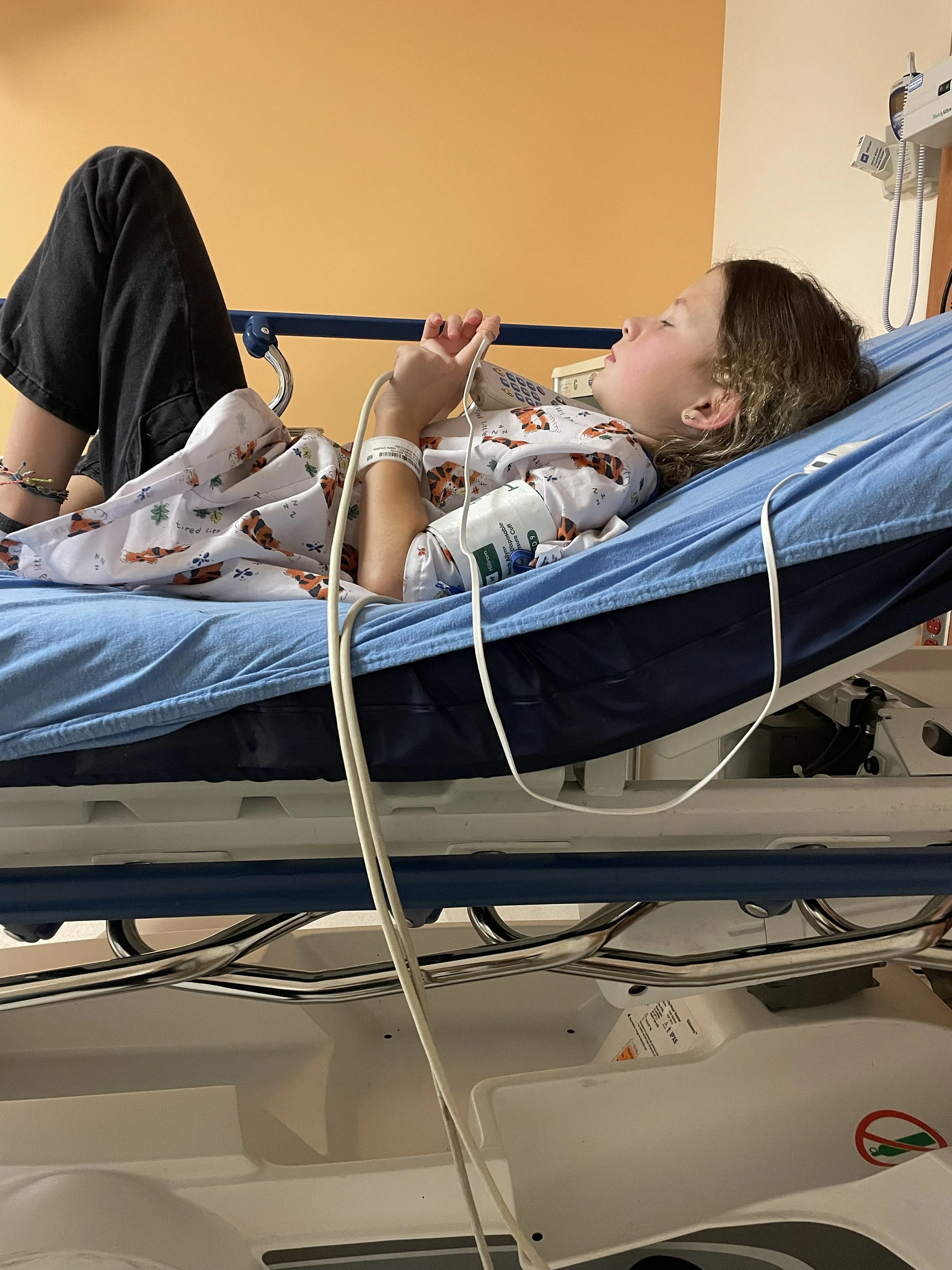 Child lying on a hospital bed with a medical gown and sensors attached.