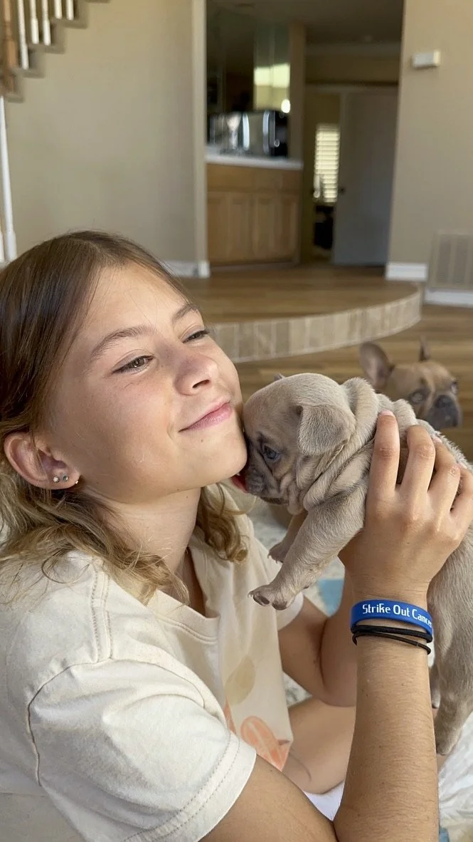 Smiling child holding a small puppy indoors