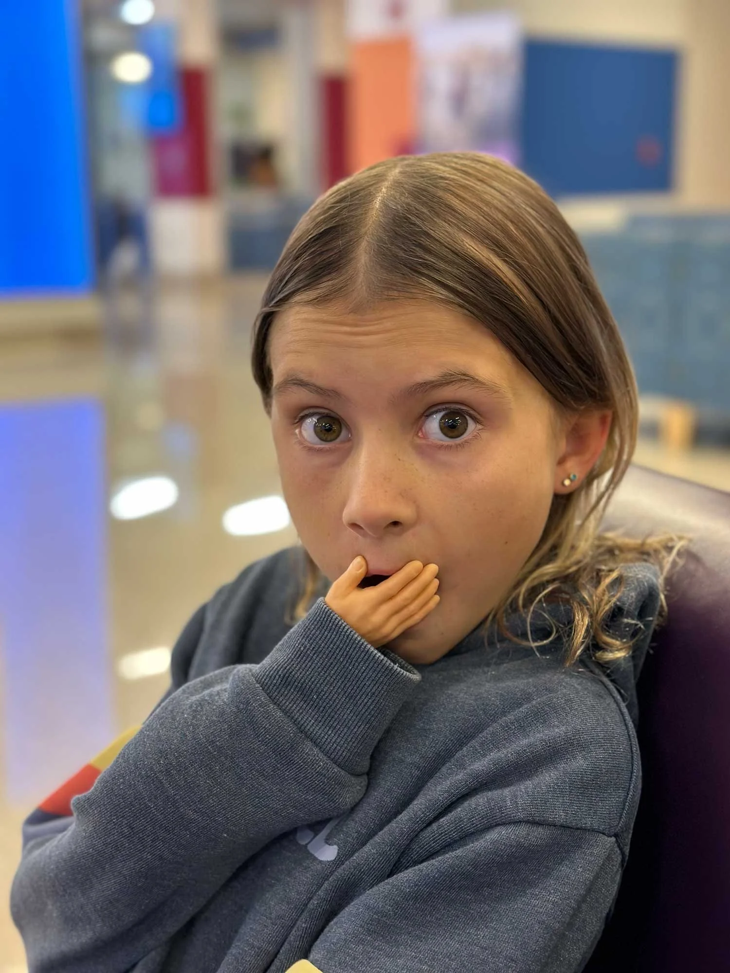 Child with a surprised expression and a small toy hand held up to their mouth.